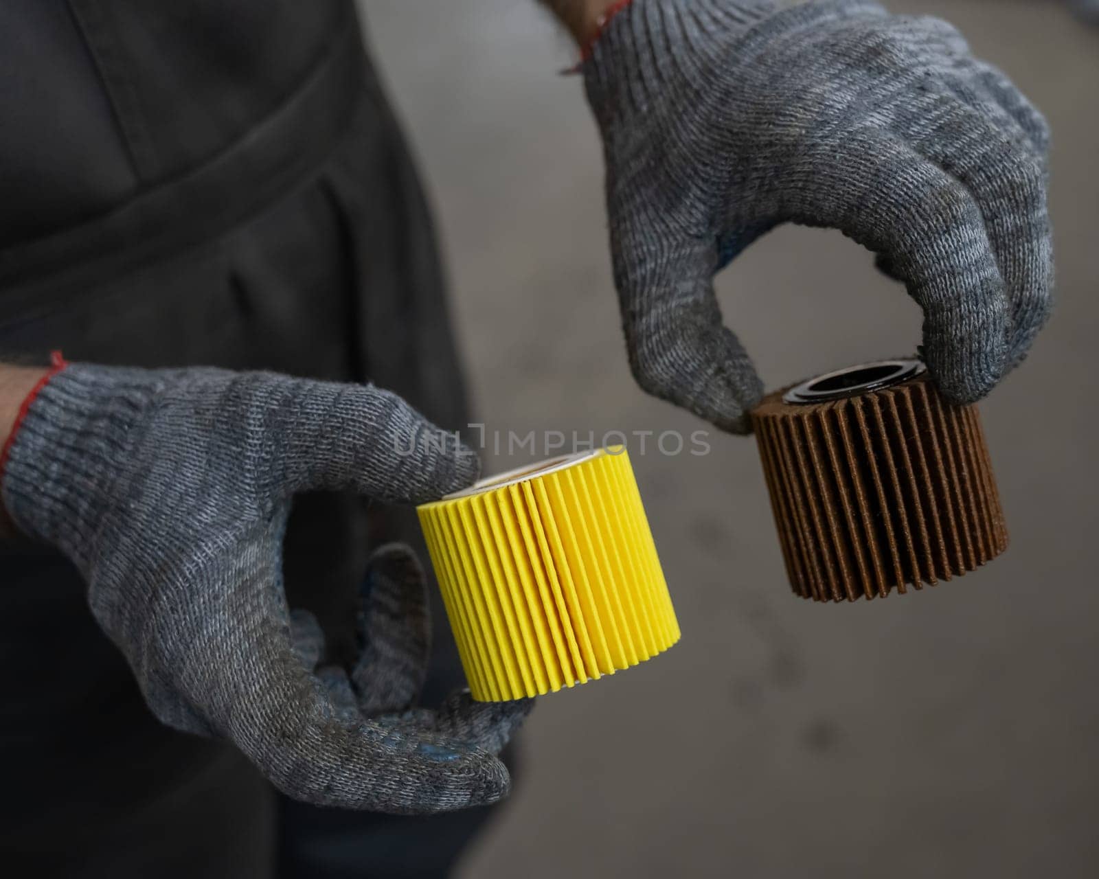 Mechanic holding old and new car oil filters. by mrwed54