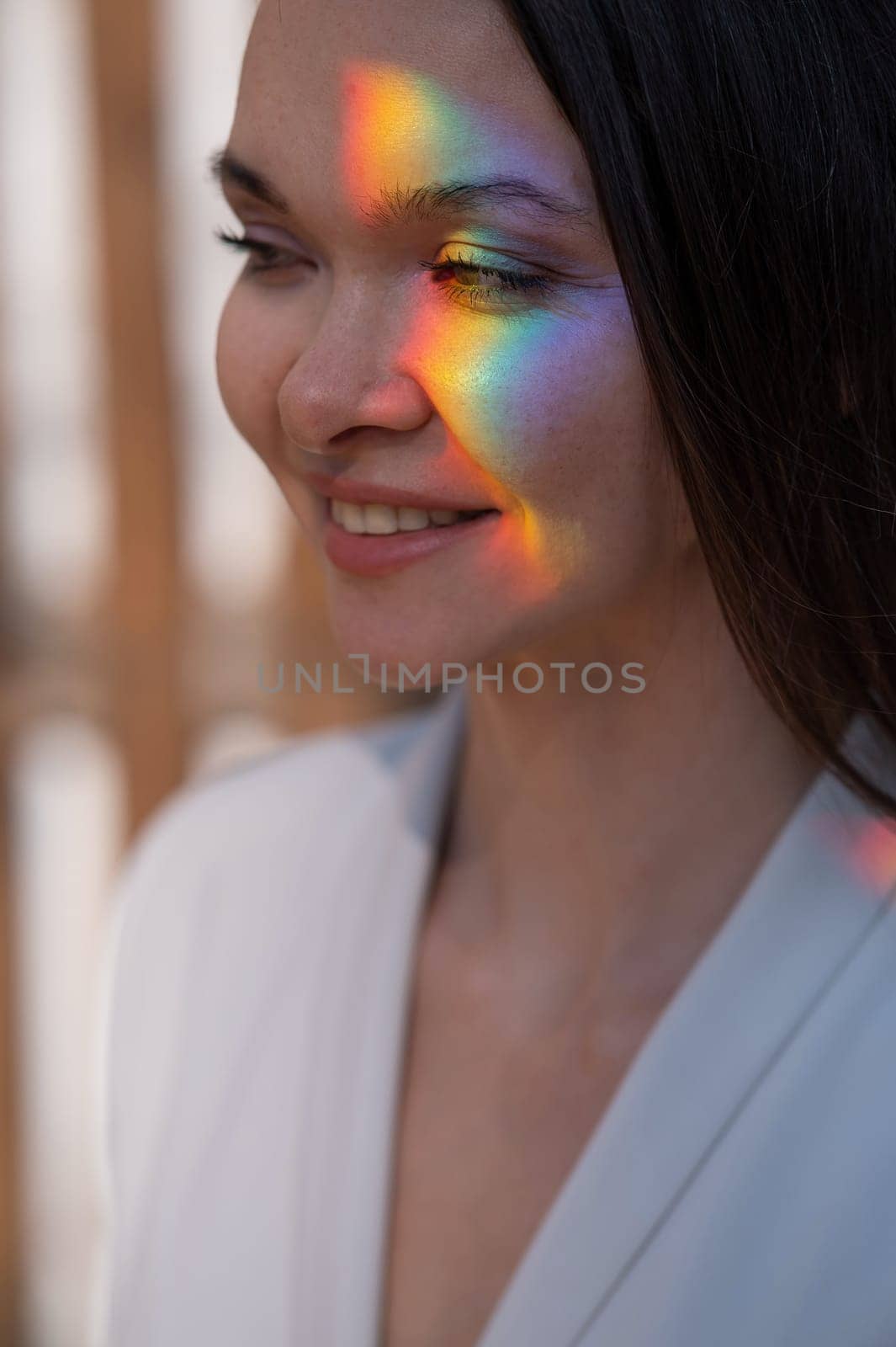 Portrait of caucasian woman with rainbow beam on her face outdoors. by mrwed54