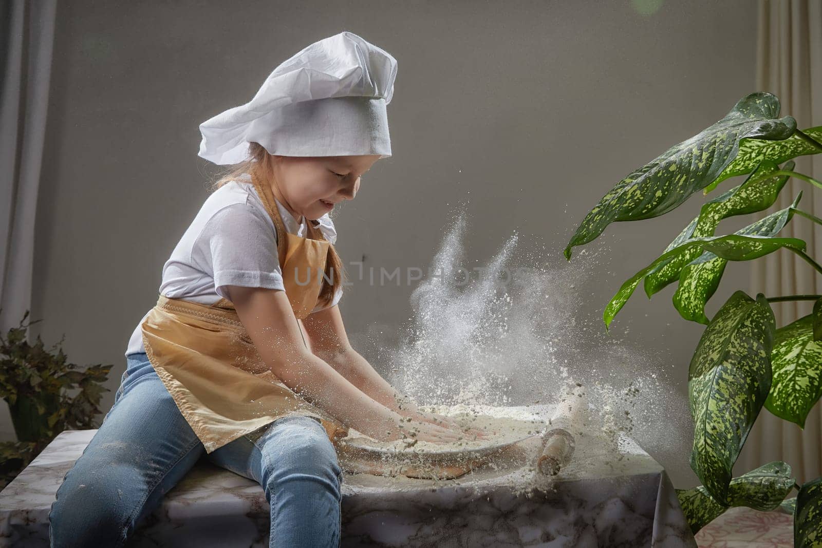 Cute oriental girl cooking in the kitchen on Ramadan, Kurban-Bairam, Eid al-Adha. Funny female child at cook photo shoot. Pancakes, Maslenitsa, Easter