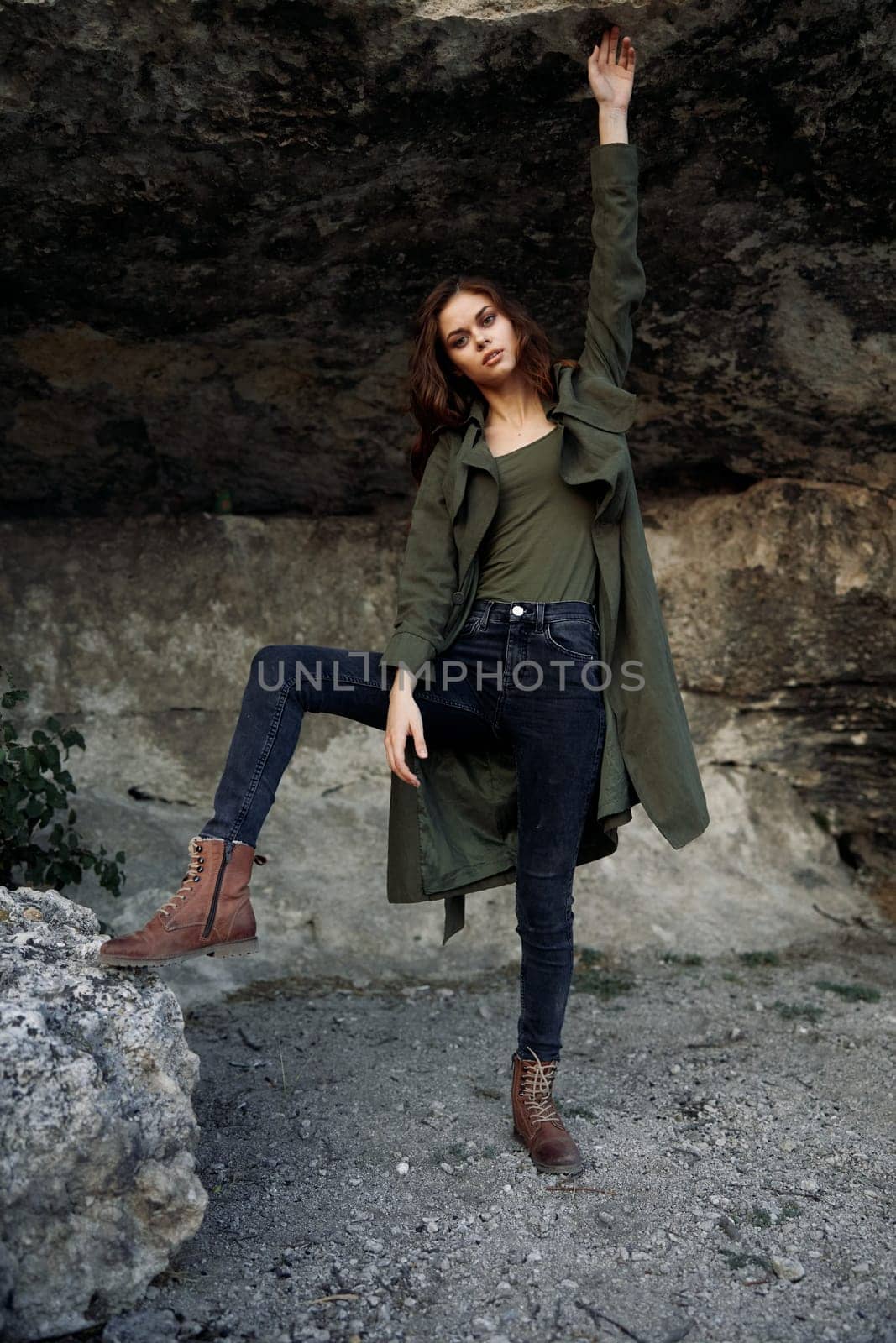 Serene woman in green coat standing on rock overlooking majestic rock formation by Vichizh