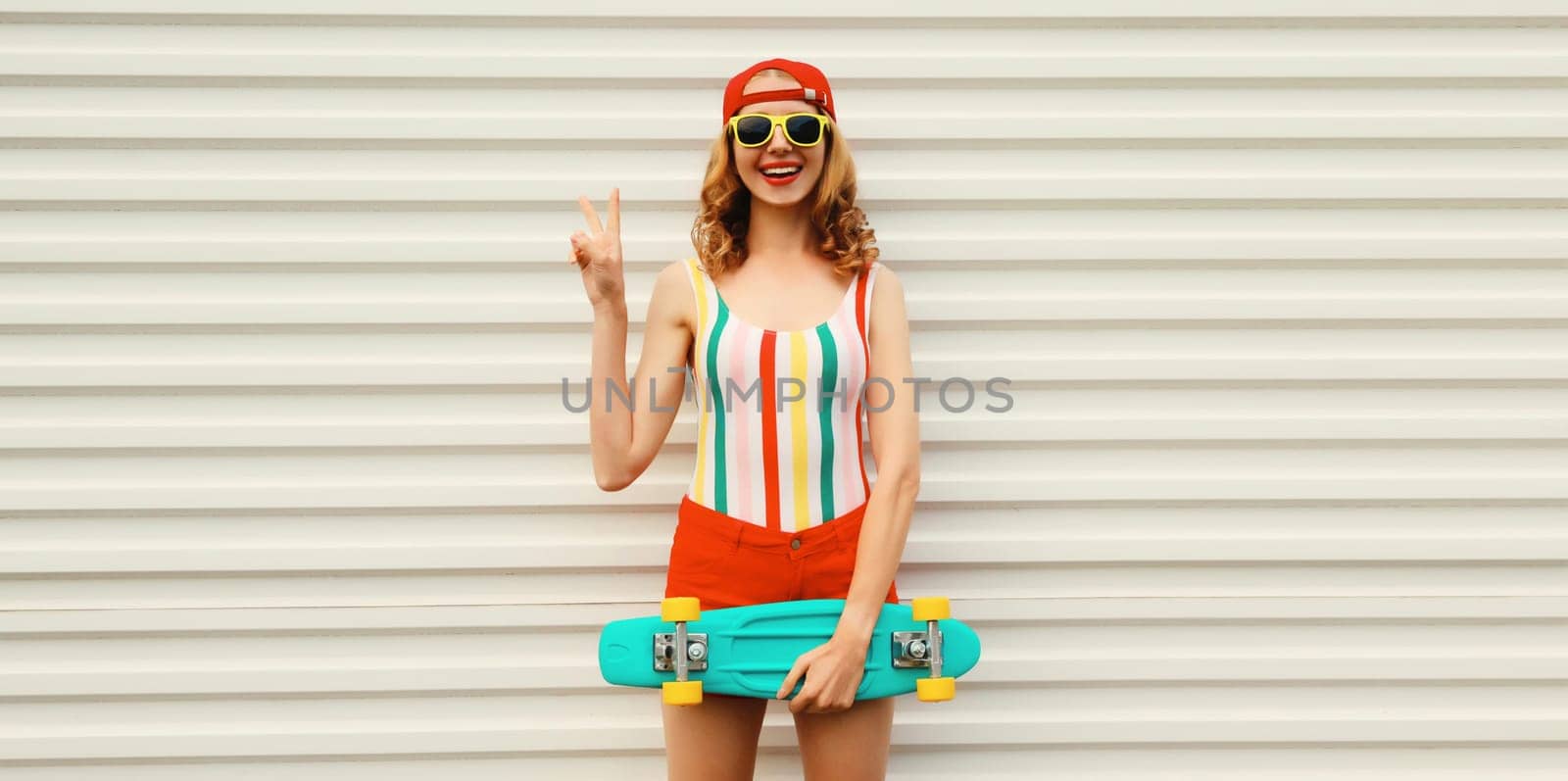 Summer portrait of happy cheerful stylish young woman with skateboard posing in colorful clothes by Rohappy