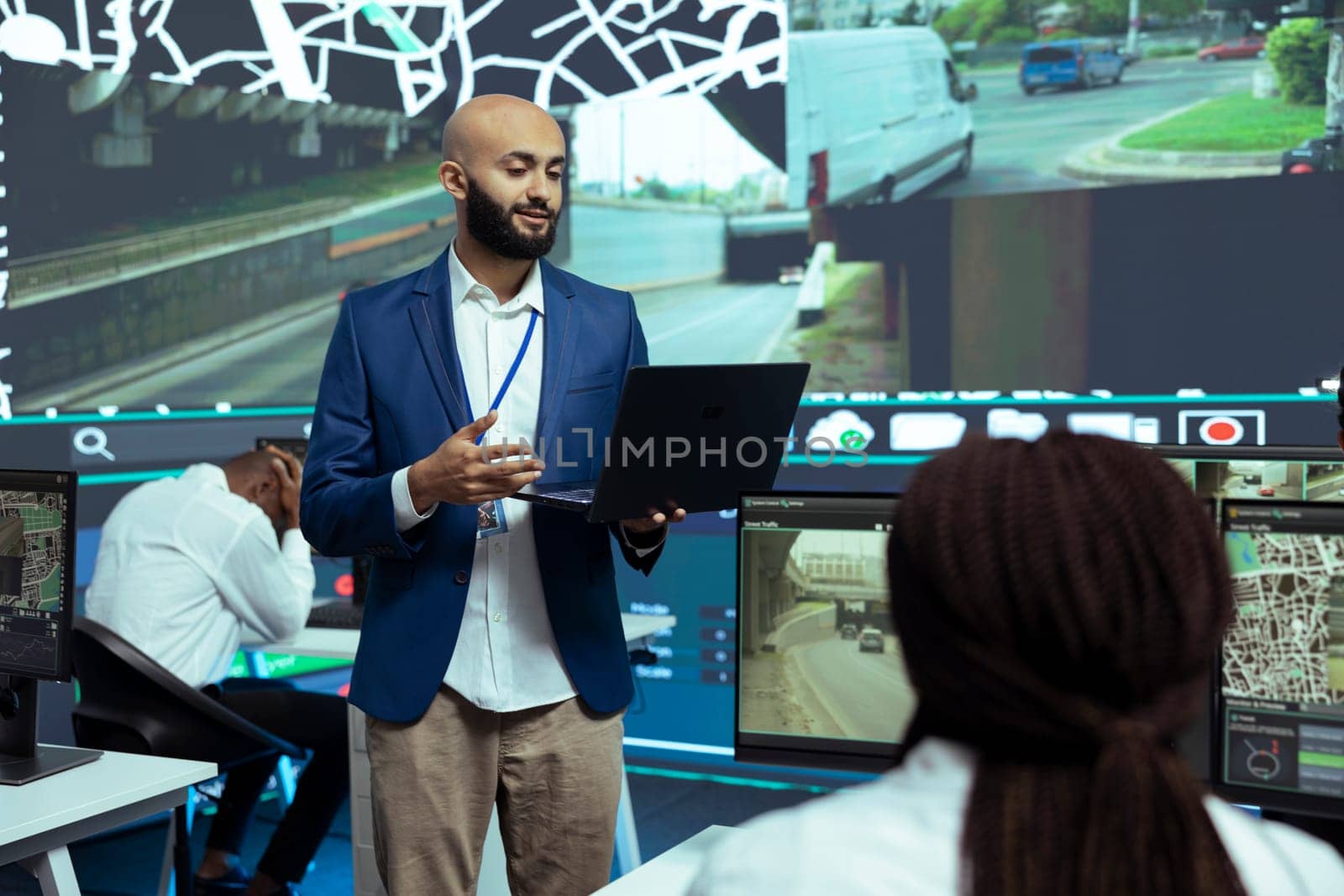 Middle eastern team leader instructing his staff to track and trace delivery trucks via satellite map, ensuring fast cargo shipment. Employees guiding the drivers through city traffic.