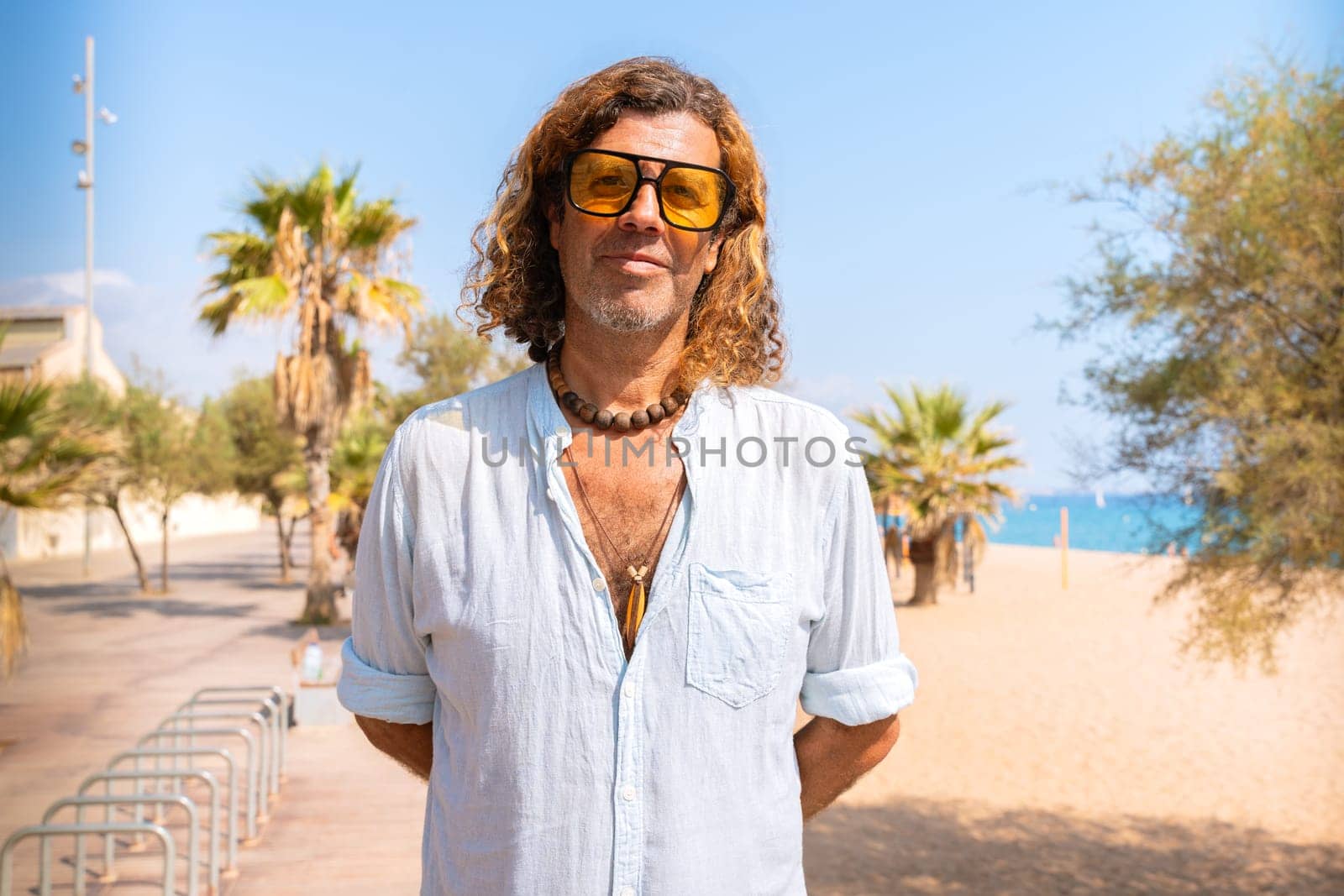 Caucasian adult man wearing smiling sunglasses looking at camera. Man on vacation on the coast.