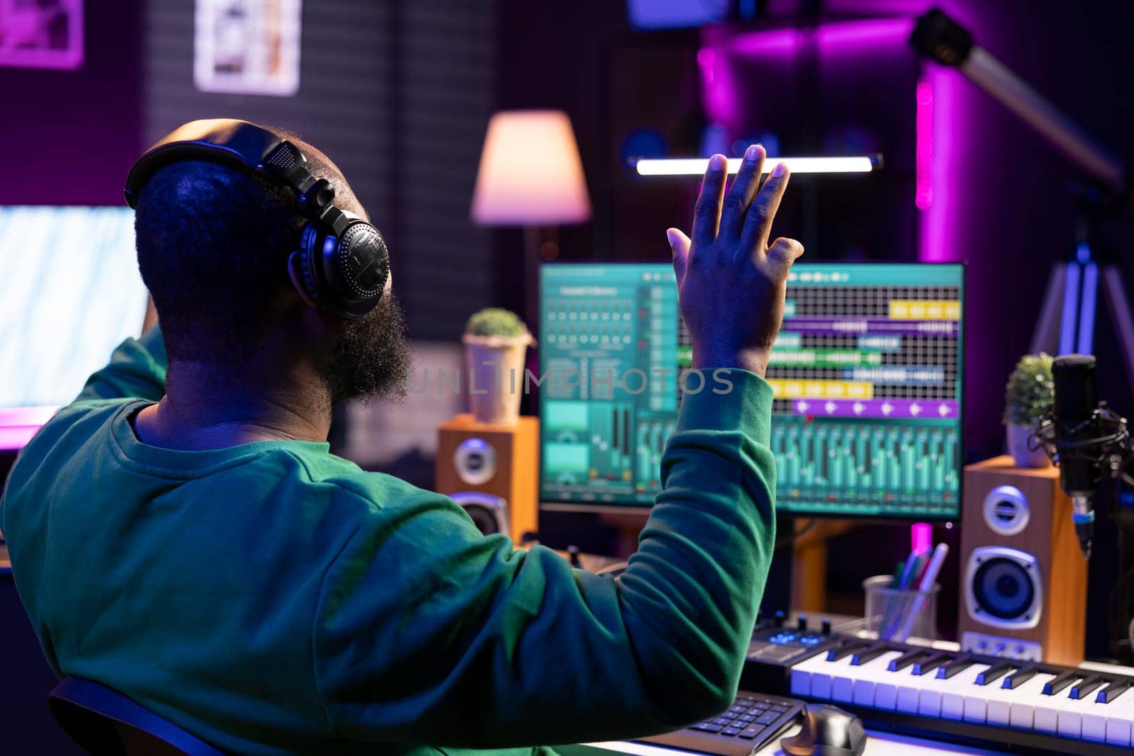 African american skilled audio technician counting down before recording a song, doing a session in his home studio. Producer operating on mixing console and digital software, stereo gear.