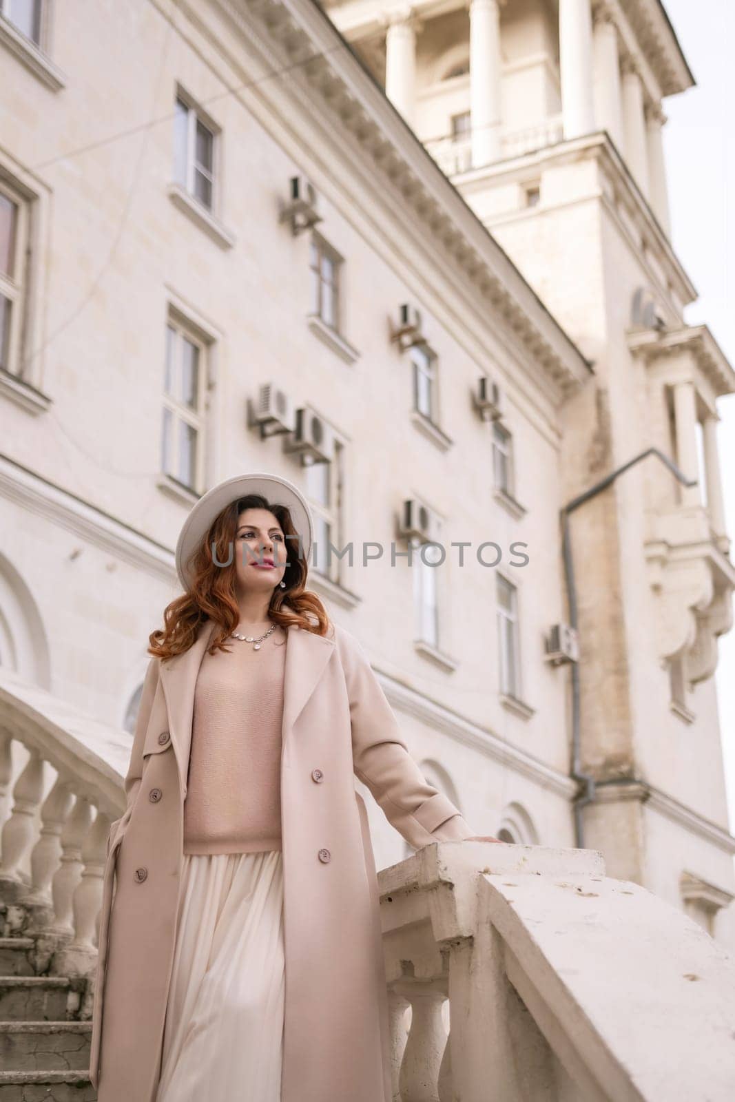 woman in elegant coat and hat against an intricate architectural backdrop, harmoniously blending modern fashion with historical allure. The soft daylight adds to its timeless appeal