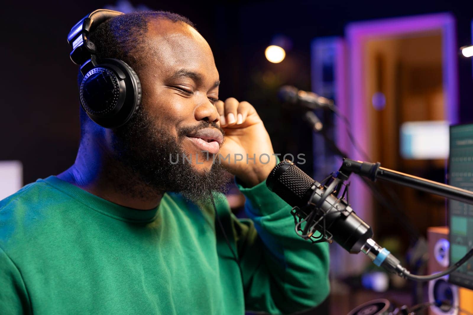 Confident songwriter performing a tune on microphone in home studio, recording his song and editing in post production. Performer artist singing aloud and using stereo equipment. Close up.