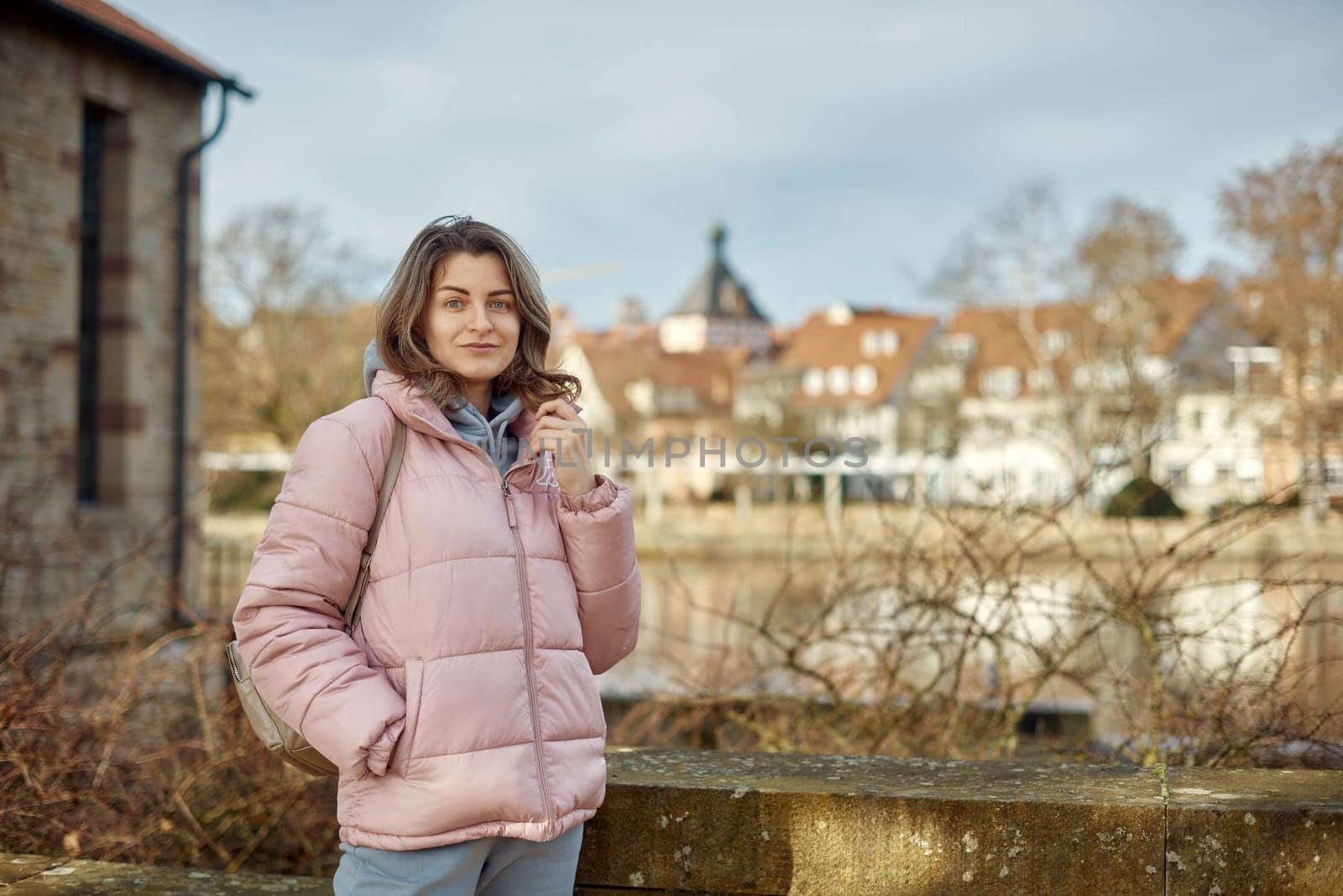 Young beautiful pretty tourist girl in warm hat and coat with backpack walking at cold autumn in Europe city enjoying her travel in Bietigheim-Bissingen, Deutschland. Outdoor portrait of young tourist woman enjoying sightseeing by Andrii_Ko