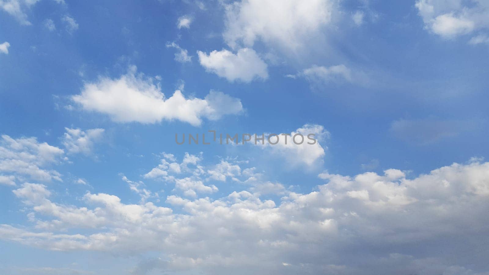 Above, the azure expanse is decorated with fluffy cumulus clouds, fashioning a picturesque natural vista.
