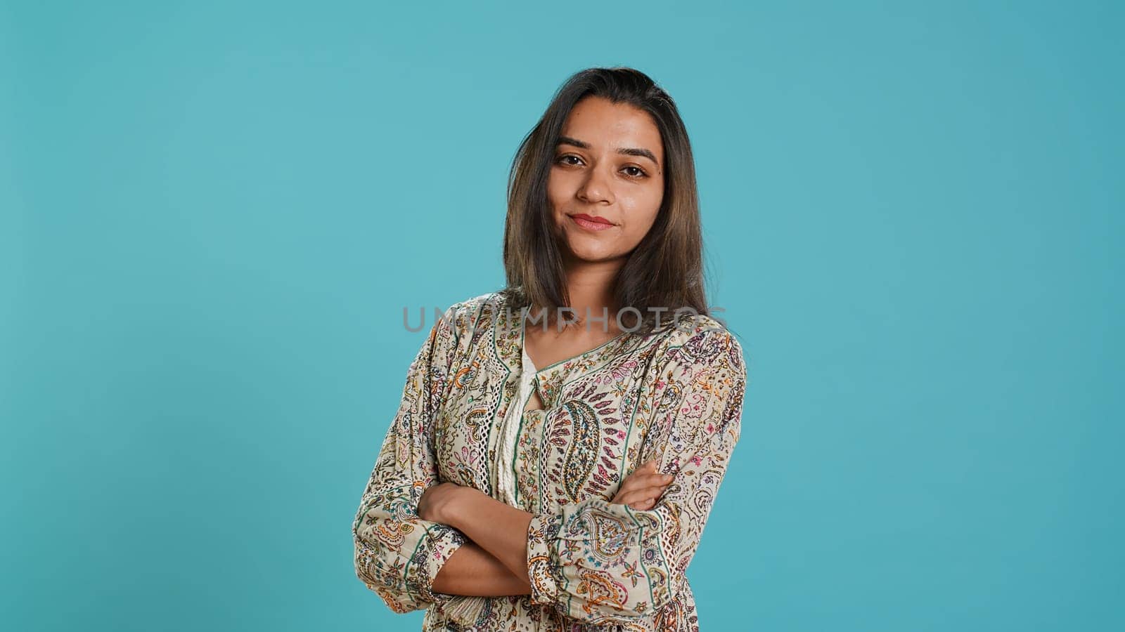Portrait of cheerful friendly indian woman smiling, looking pleased, isolated over studio background. Happy person in traditional attire having positive facial expression, feeling satisfied, camera A