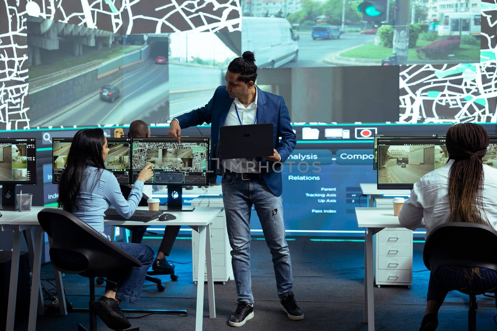 Indian coordinator offers instructions for his staff in control center monitoring room, following delivery trucks with gps coordinates on satellite map. Agency employees provide support for couriers.