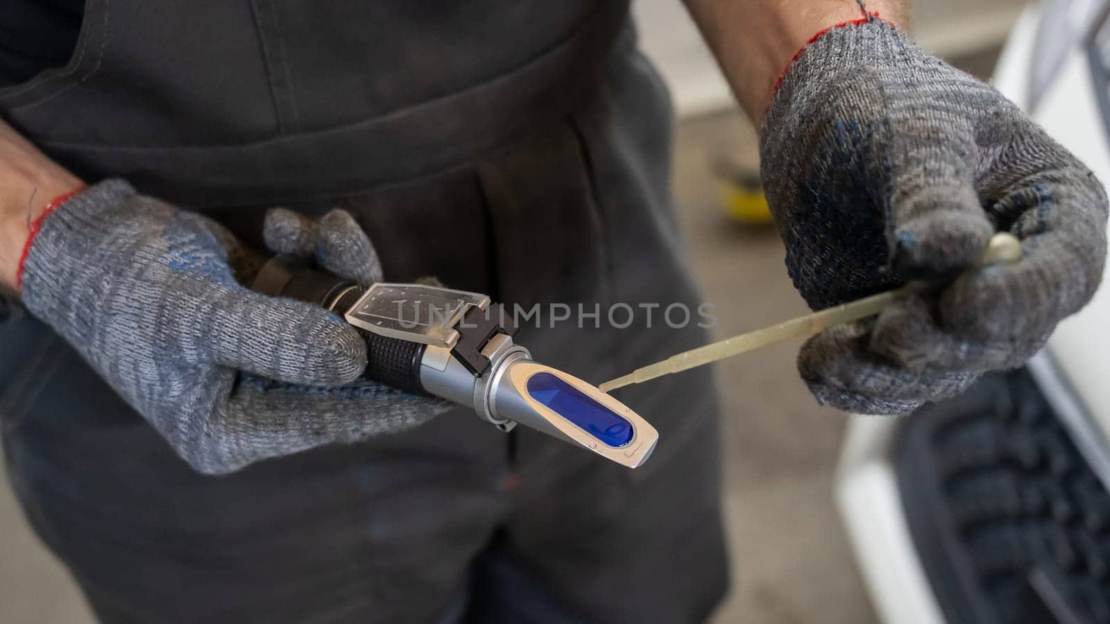 A mechanic uses a Refractometer in a car service. Portable optical device for determining the freezing point of antifreeze