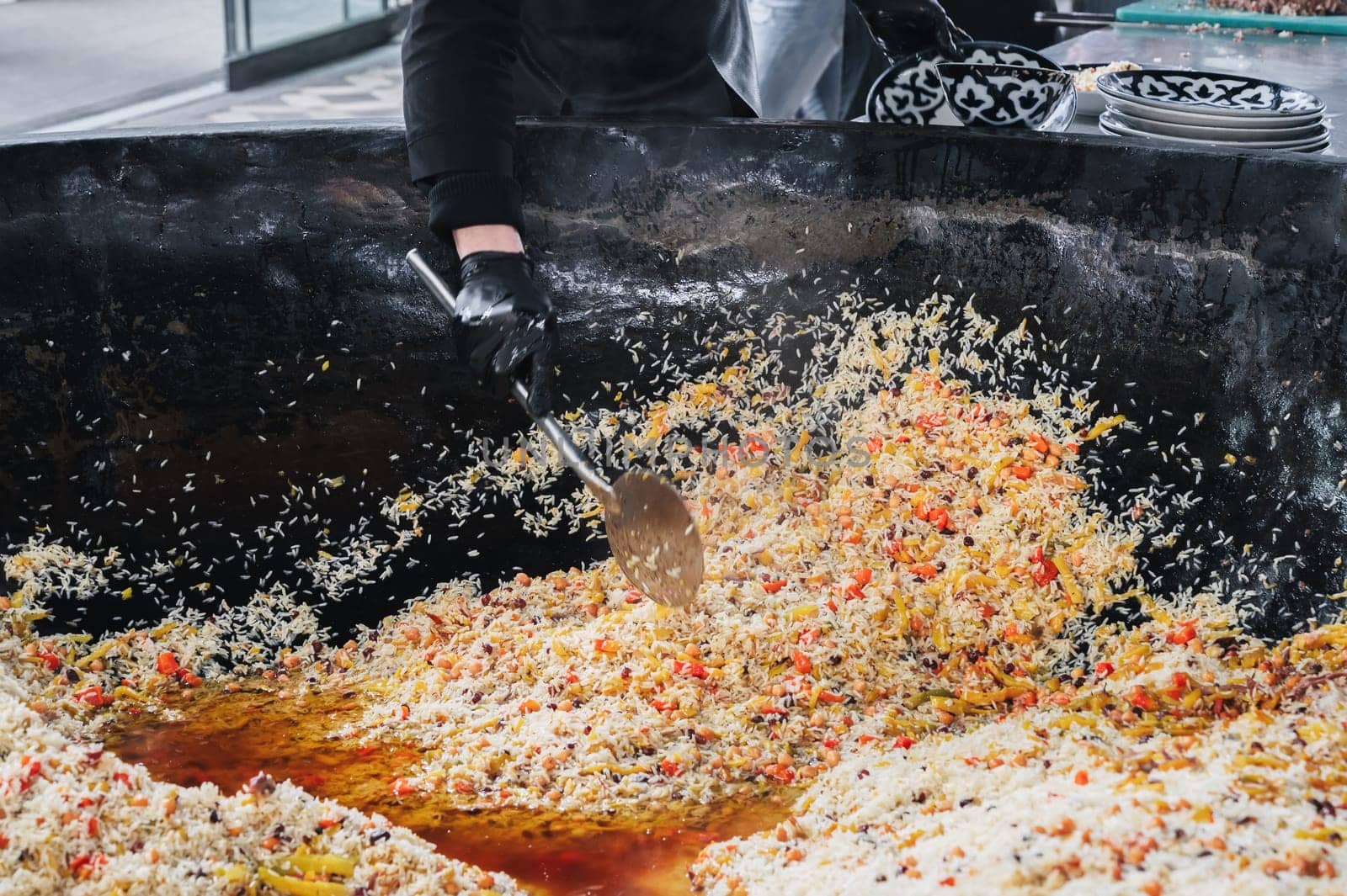 man cook puts cooked Uzbek pilaf from cauldron on plate. Traditional Oriental Arabic cuisine. Central Asian Pilaf Center Besh Qozon in Uzbekistan in Tashkent