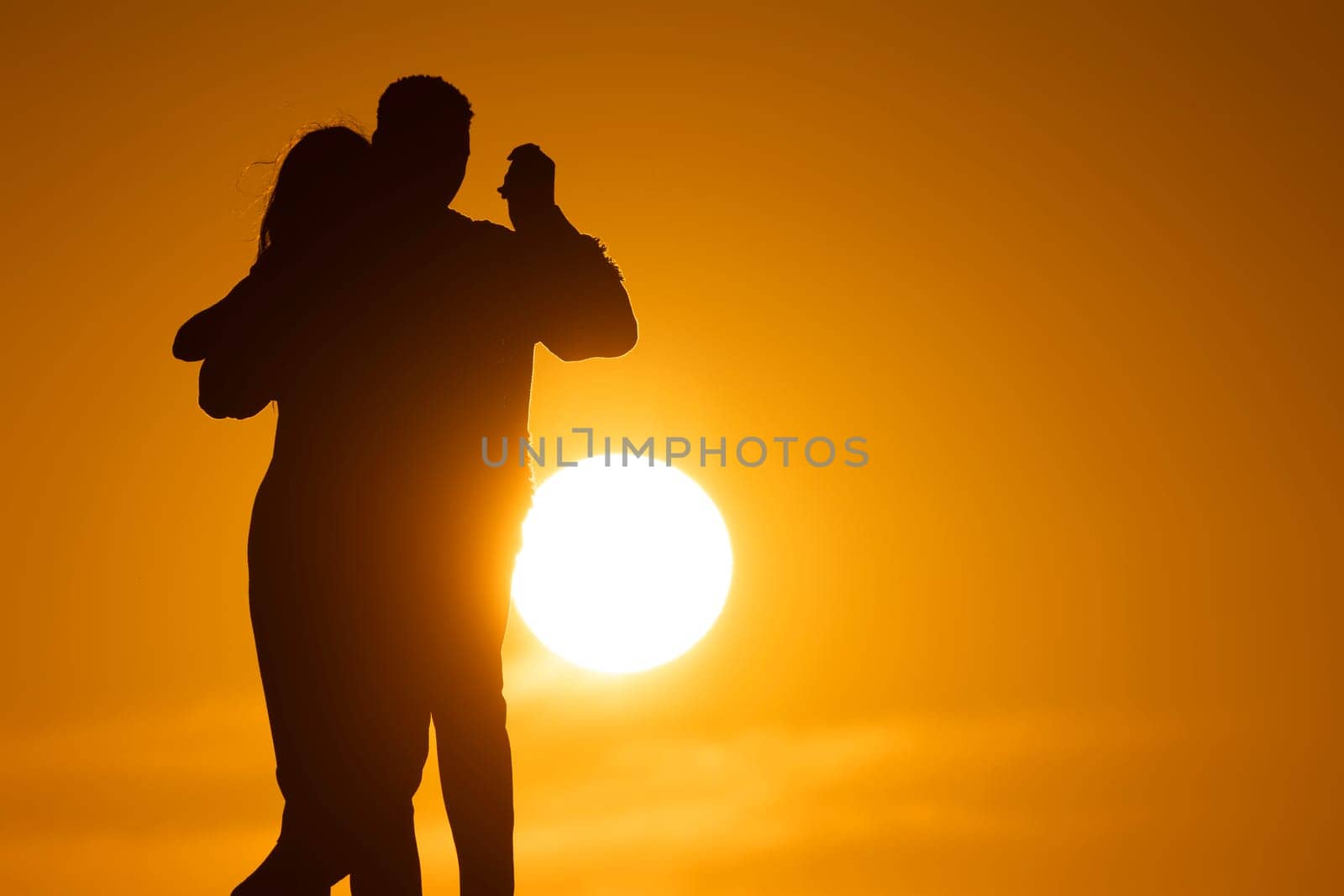 A couple is dancing in the sun, with the sun in the background. Scene is romantic and joyful