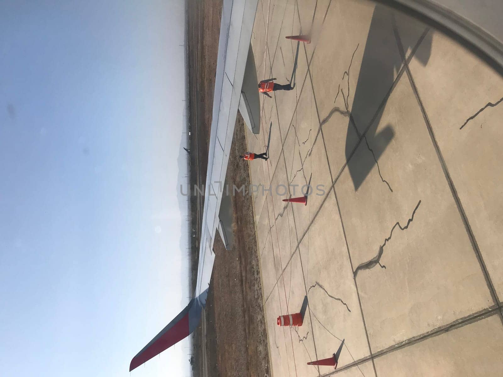 Ground crew member directing an airplane on the airport apron, seen through a cabin window