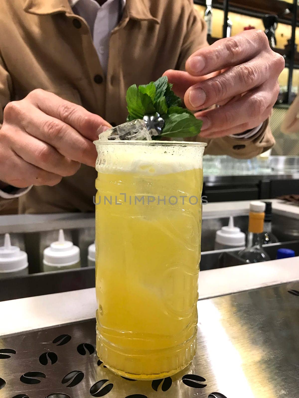 Close-up of a bartender's hands adding a mint garnish to a crafted cocktail