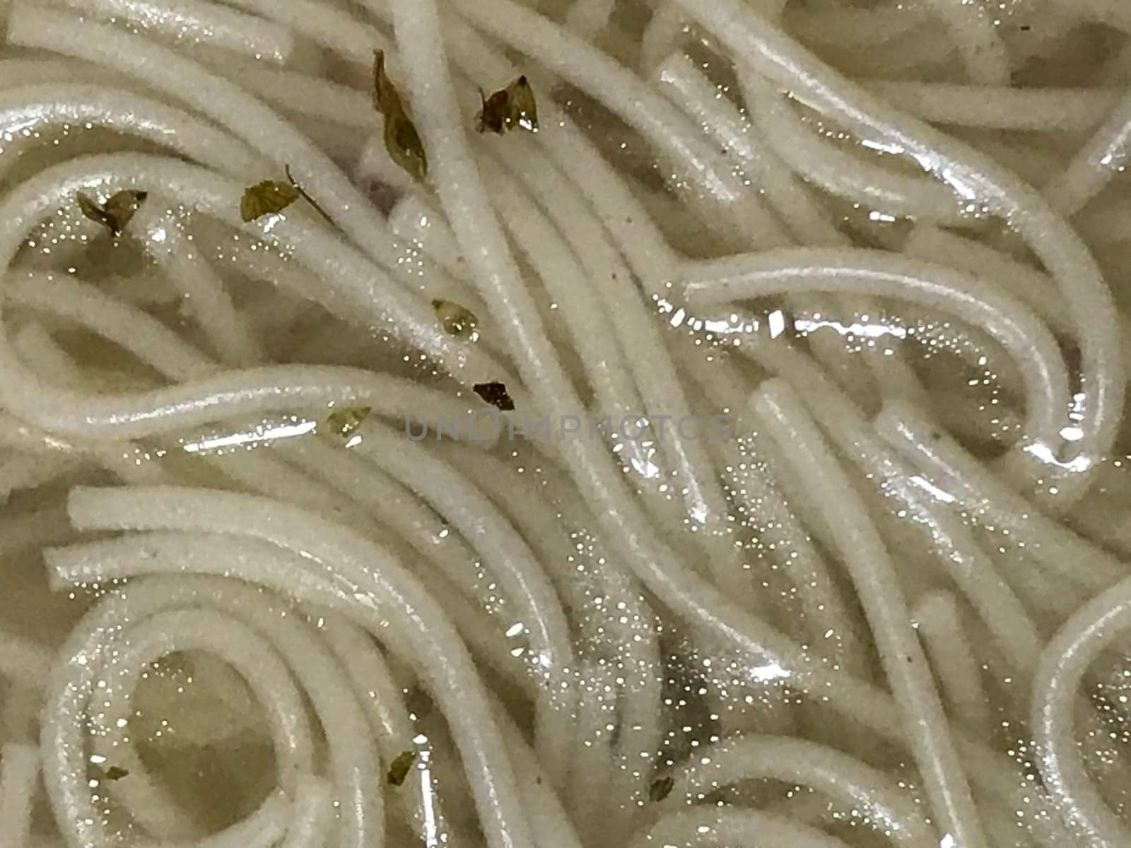Detailed view of freshly cooked noodle strands with specks of green herbs