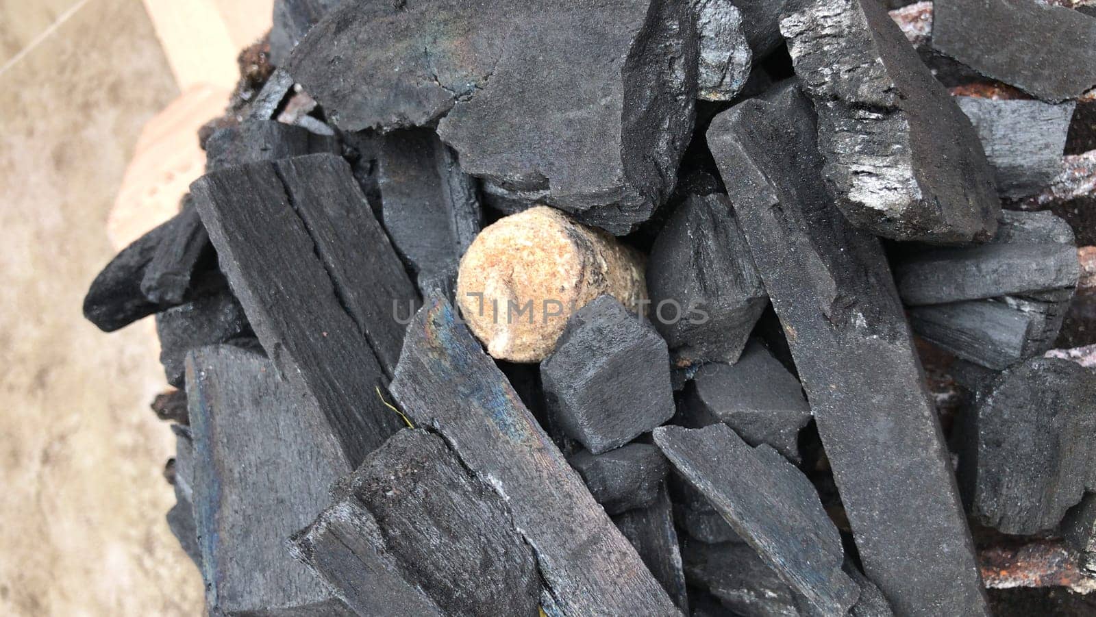 Close-up of a pile of charcoal pieces with a single round stone nestled amidst the black