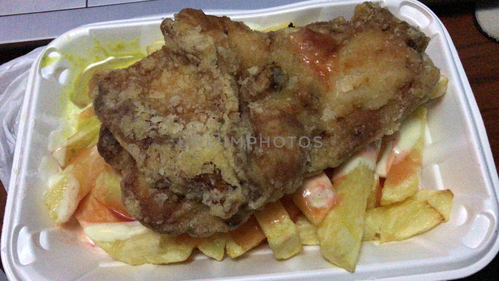 Crispy fried chicken paired with golden fries and salad in a white styrofoam container
