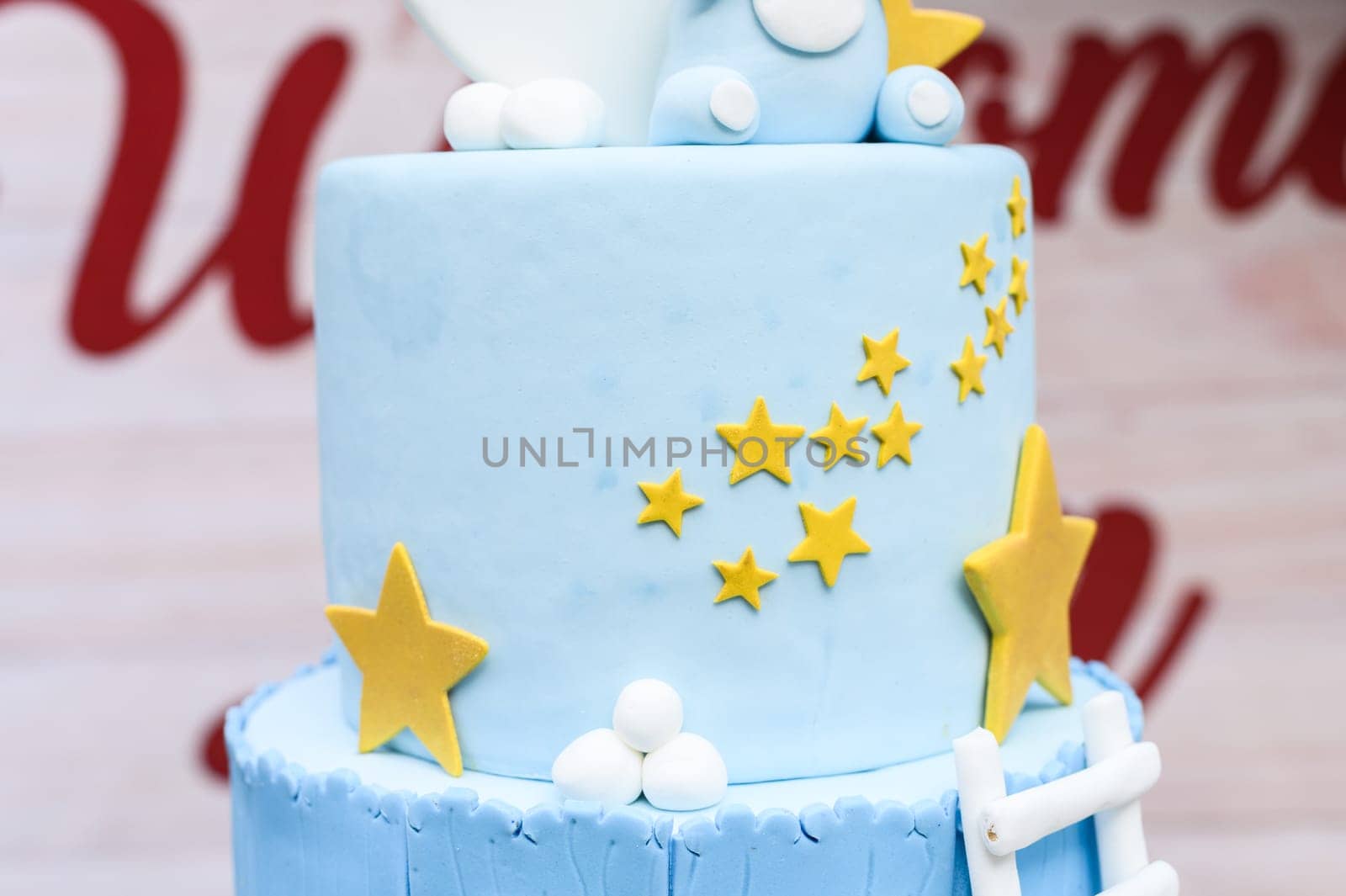 Close-up of a blue fondant cake decorated with yellow stars and white accents for celebrations