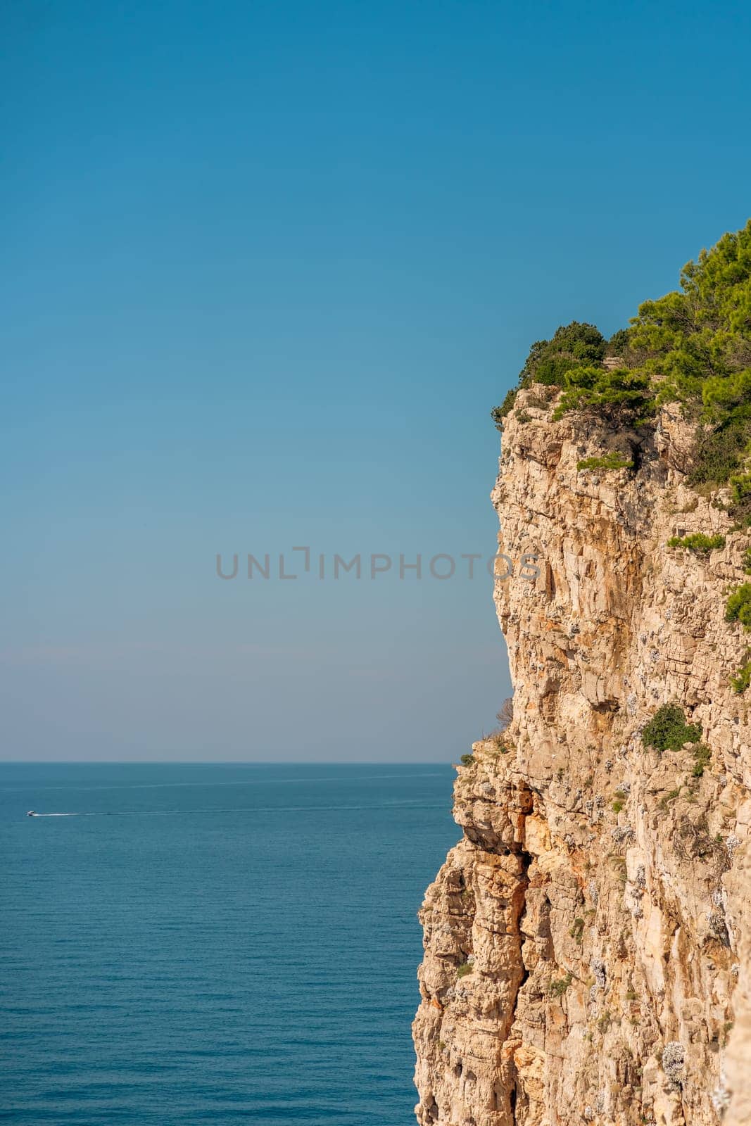 Sheer cliff in sunlight, blue water and sky in Telascica National Park, Croatia by Popov