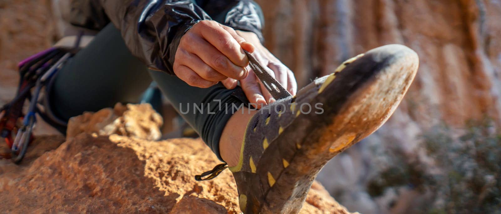 A young girl puts on special climbing shoes on her legs before climbing outdoor training, hands and feet close-up. A woman leads an active lifestyle, is involved in mountaineering and rock climbing.