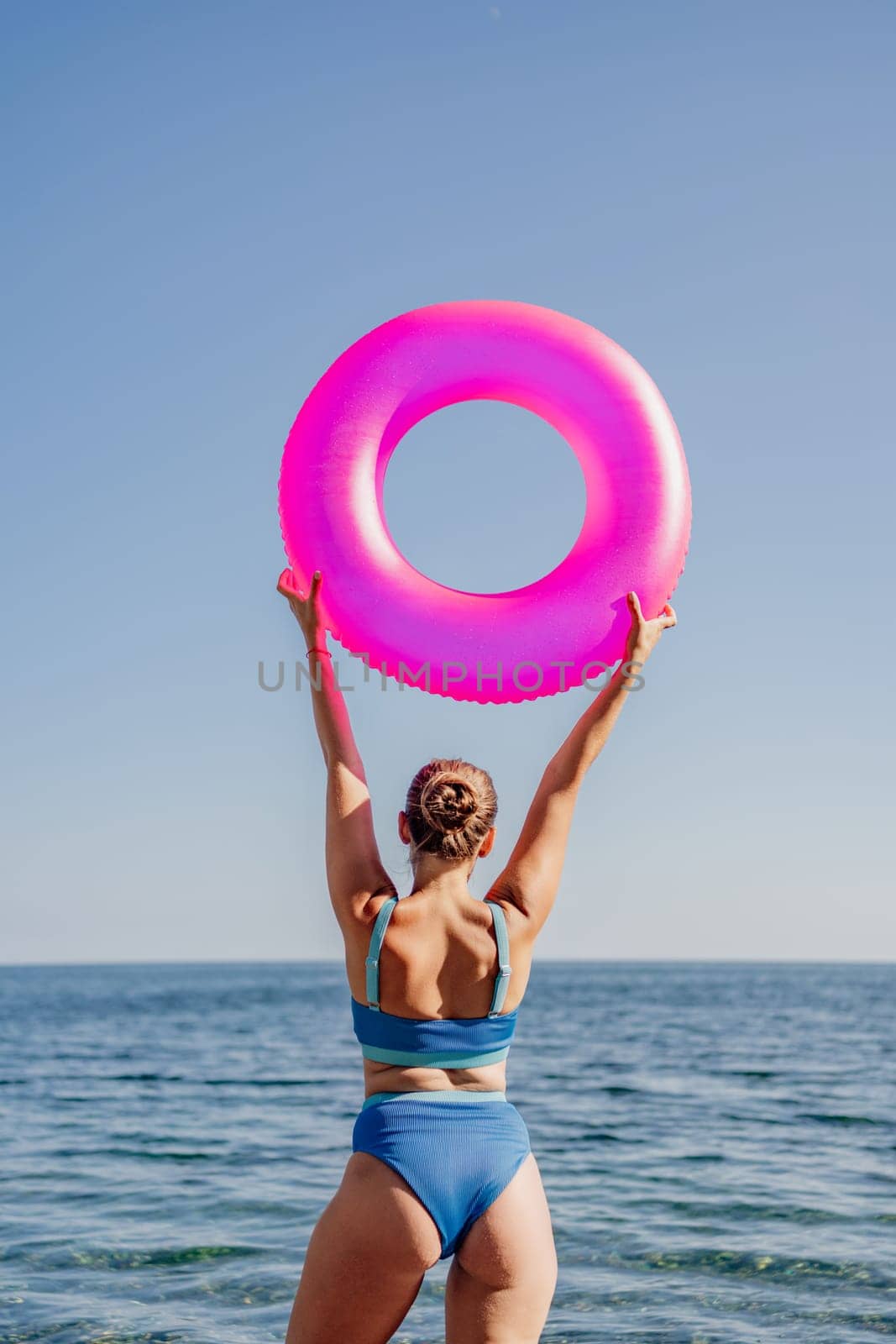 A woman is holding a pink inflatable ring in the air by Matiunina