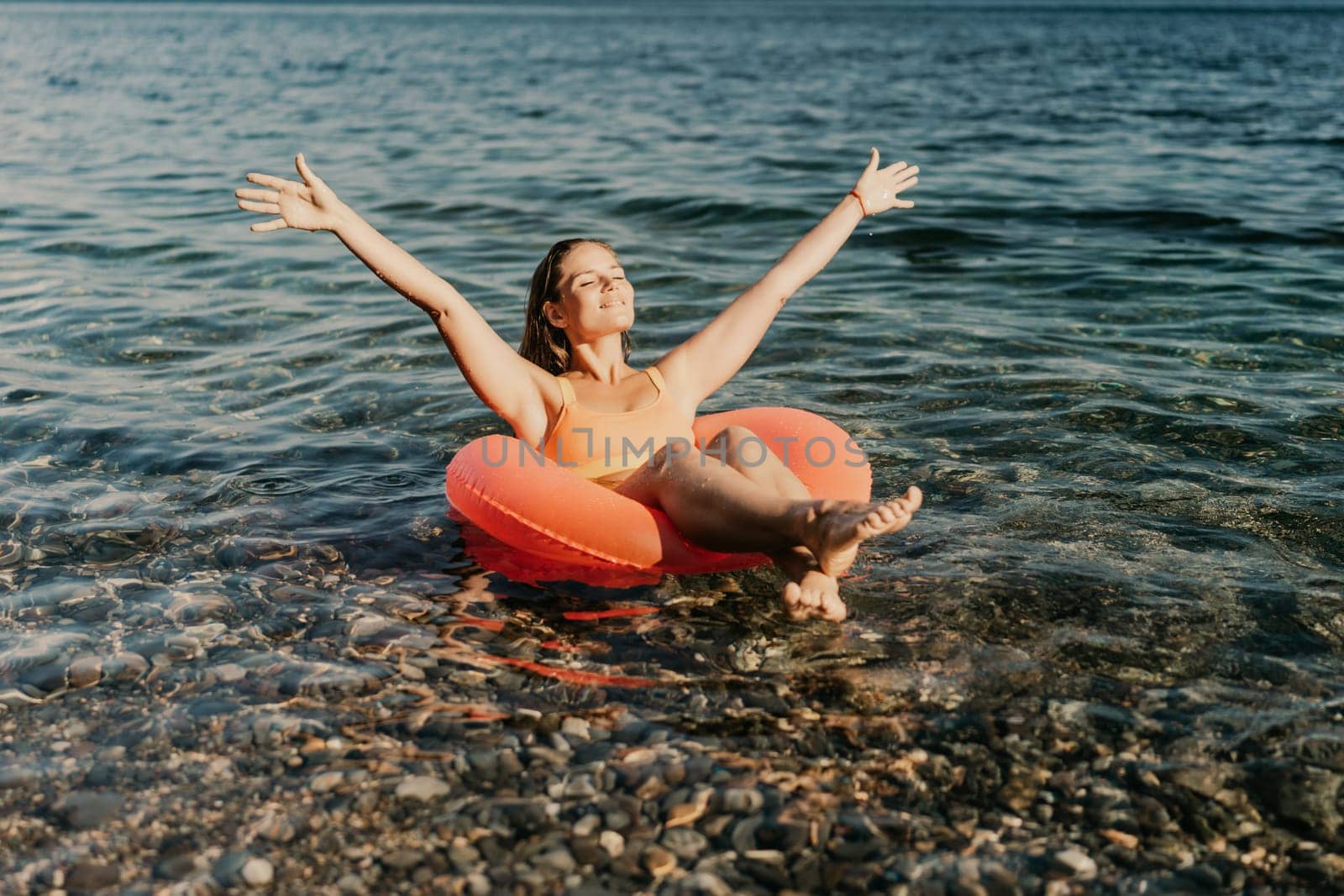 A woman is floating in a red inflatable raft on a body of water. She is smiling and she is enjoying herself