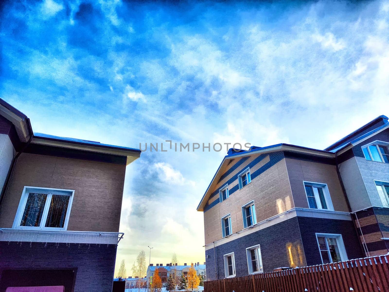 Suburban Street View With Striking Clouds at Dusk. Residential houses under vibrant evening sky with textured clouds