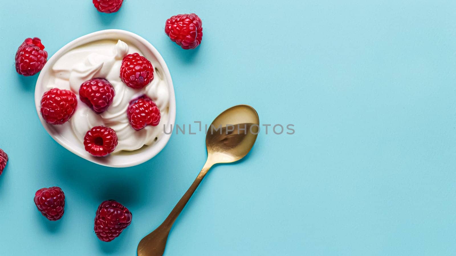 Golden spoon with creamy yoghurt and topped with fresh raspberries by Anneleven