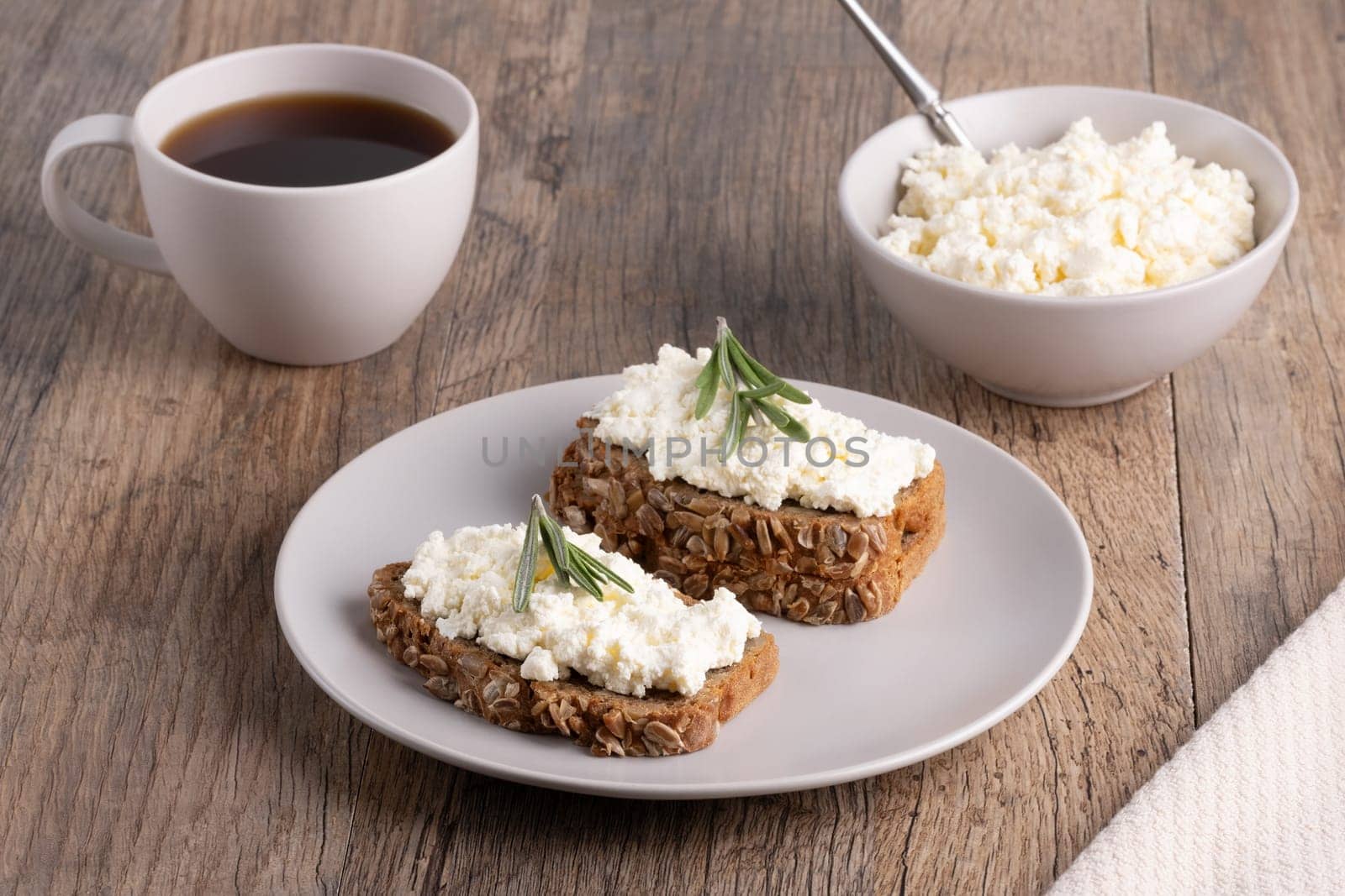 Homemade rye bread with cottage cheese in a plate and coffee. Healthy breakfast concept.