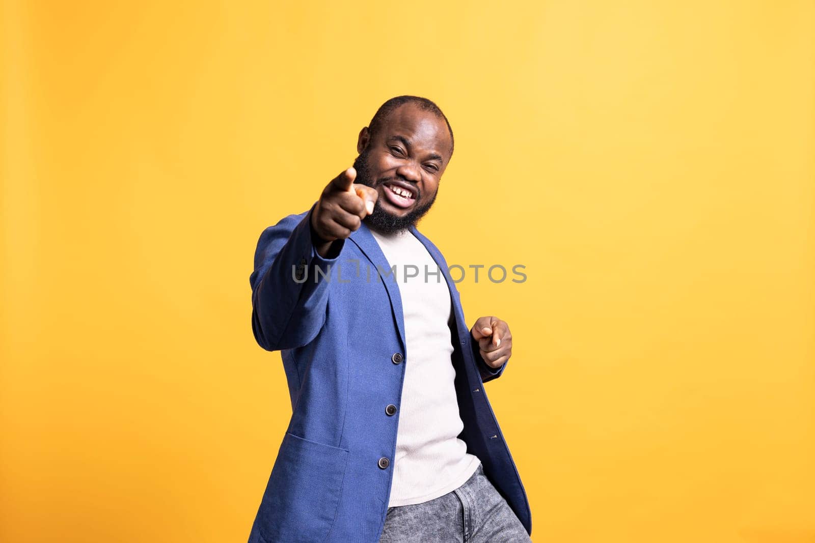 Portrait of flashy motivational speaker pointing finger to audience with determination, isolated over studio background. Expressive vigorous BIPOC lecturer showing intense emotion