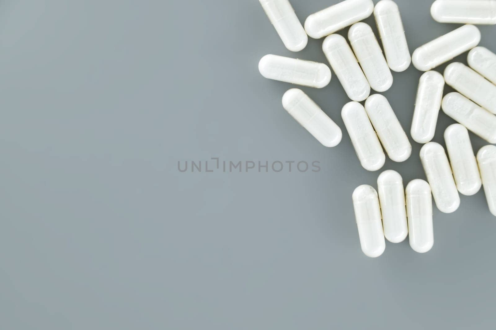 Large number of white pills scattered on a gray surface. Minimal medical, pharmaceutical concept with free copy space