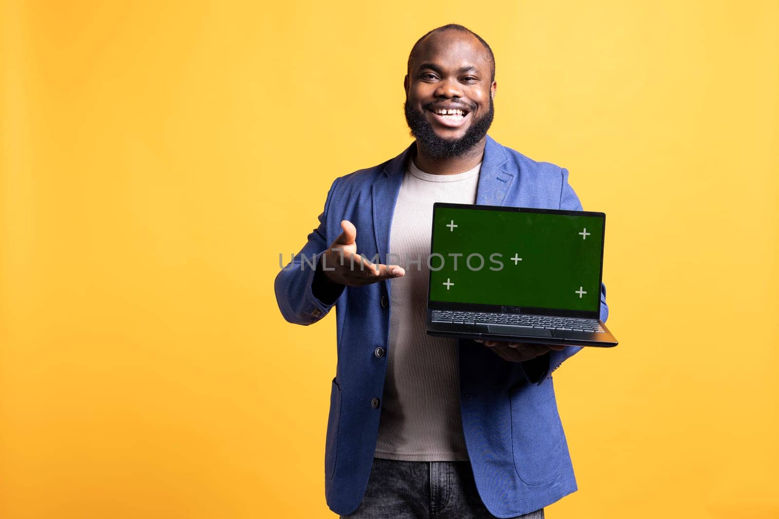 Happy african american man holding green screen laptop, doing endorsement. Cheerful BIPOC person presenting mockup notebook, doing positive evaluation, isolated over studio background