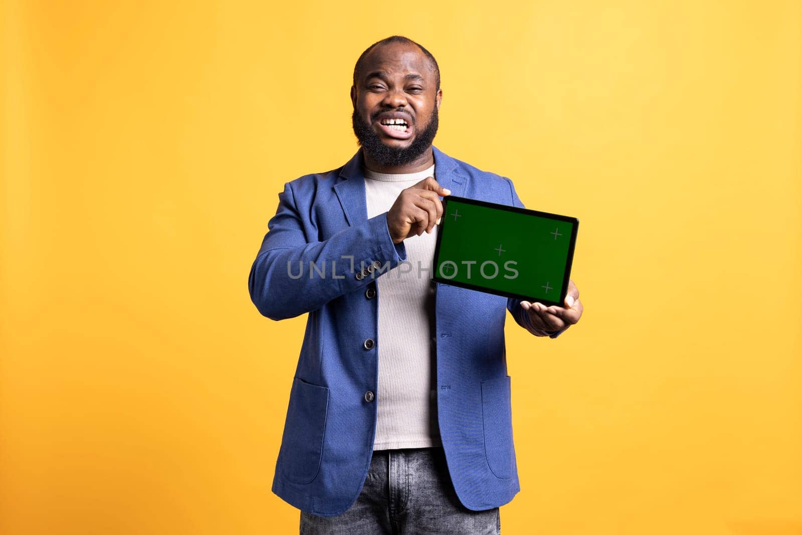 Ecstatic man excited while showing green screen tablet, studio background by DCStudio