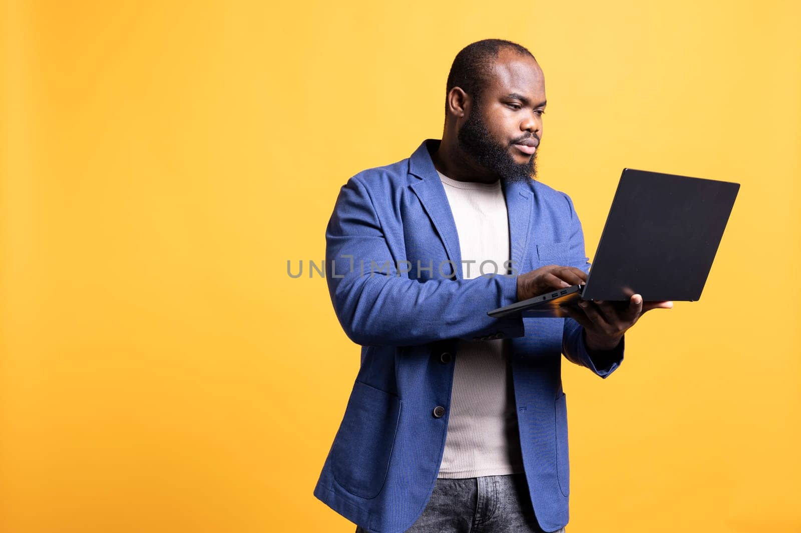 Man looking at business diagram and figures on laptop, studio background by DCStudio