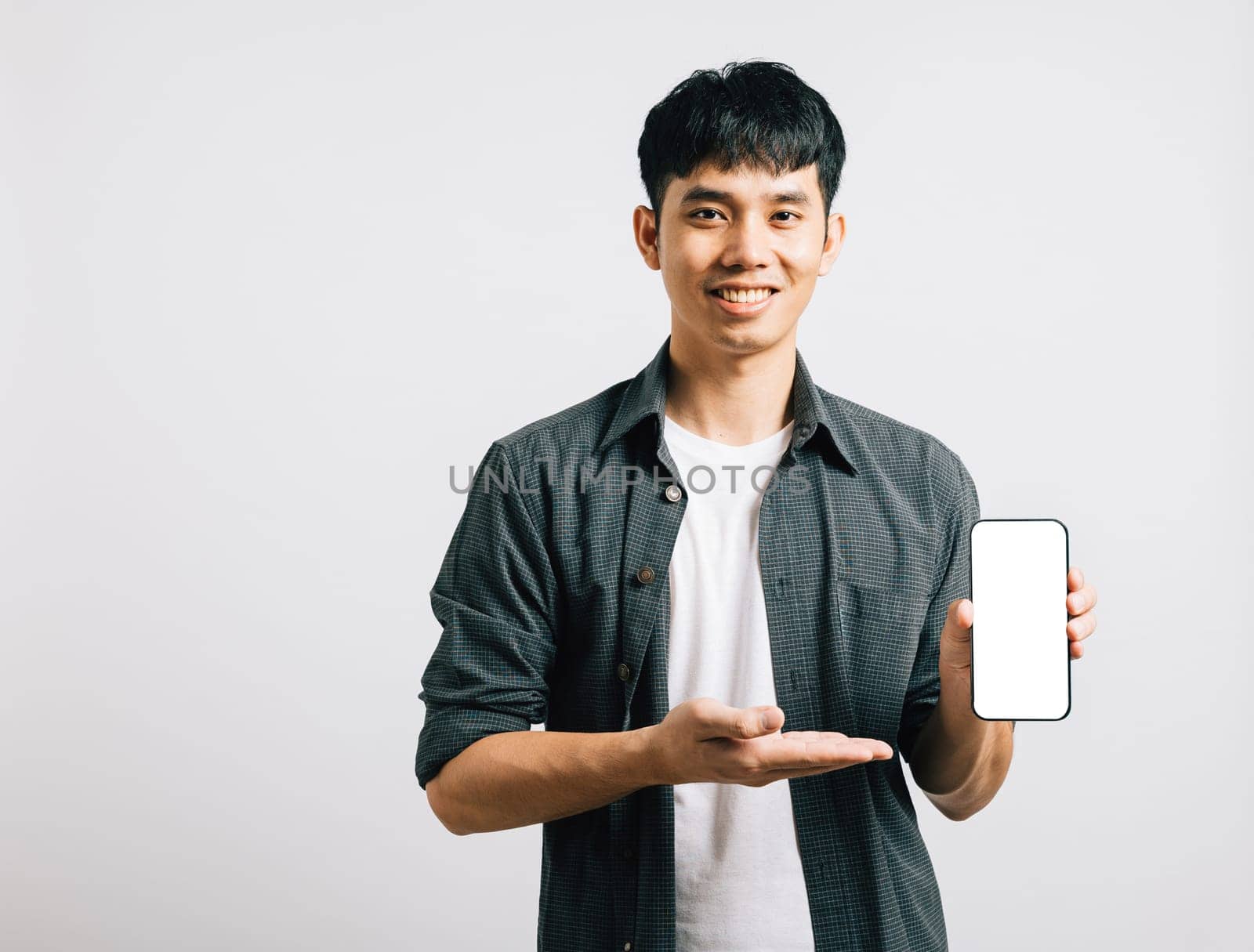 Portrait Asian smiling young man show mobile phone blank screen and hand open studio shot isolated white background, Happy excited lifestyle men hold smartphone present something on palm by Sorapop