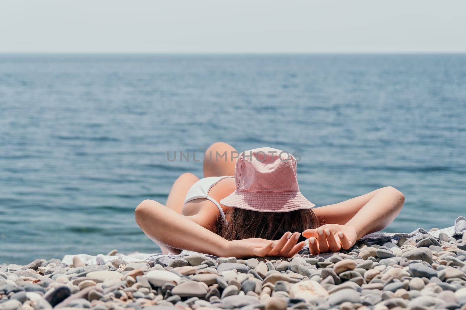 Happy smiling young woman sunbathing or tanning on a seaside beach during summer vacation. Slow motion of happy tourist in red swimsuit enjoying sun tan lying on beach chair lounge at luxury resort.