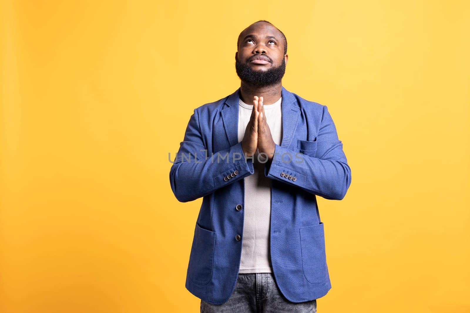 Pious african american man praying to his god, asking for forgiveness. Spiritual BIPOC man doing worship hand gesturing, confessing, begging for pardon, isolated over studio background