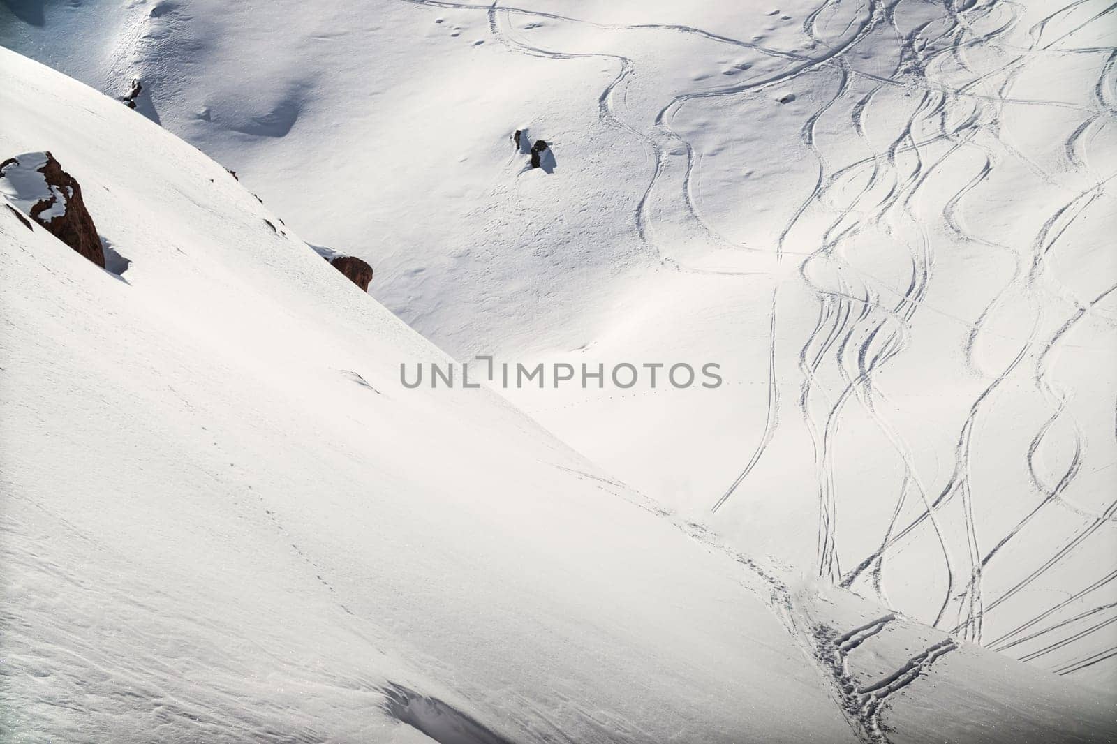 Traces on a mountain slope from skis and snowboards on unprepared high mountain slopes, holiday freeride, copy space.