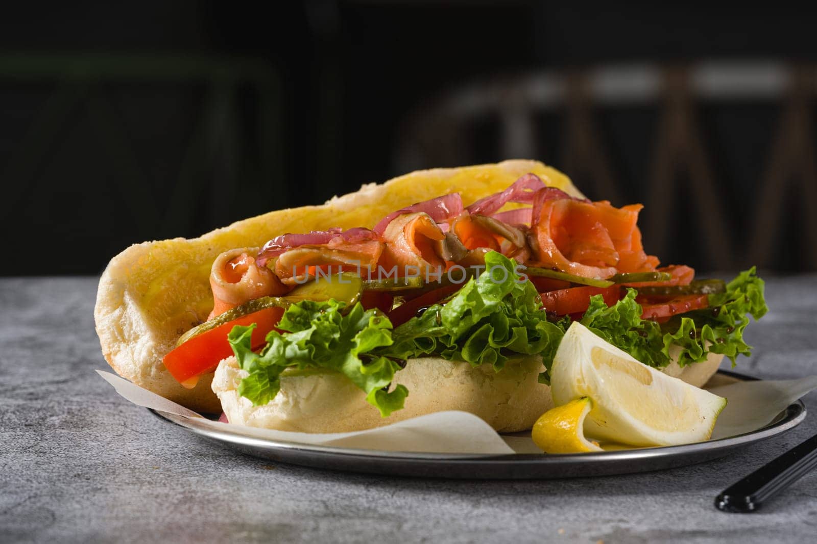 Smoked salmon sandwich on metal plate on stone table by Sonat