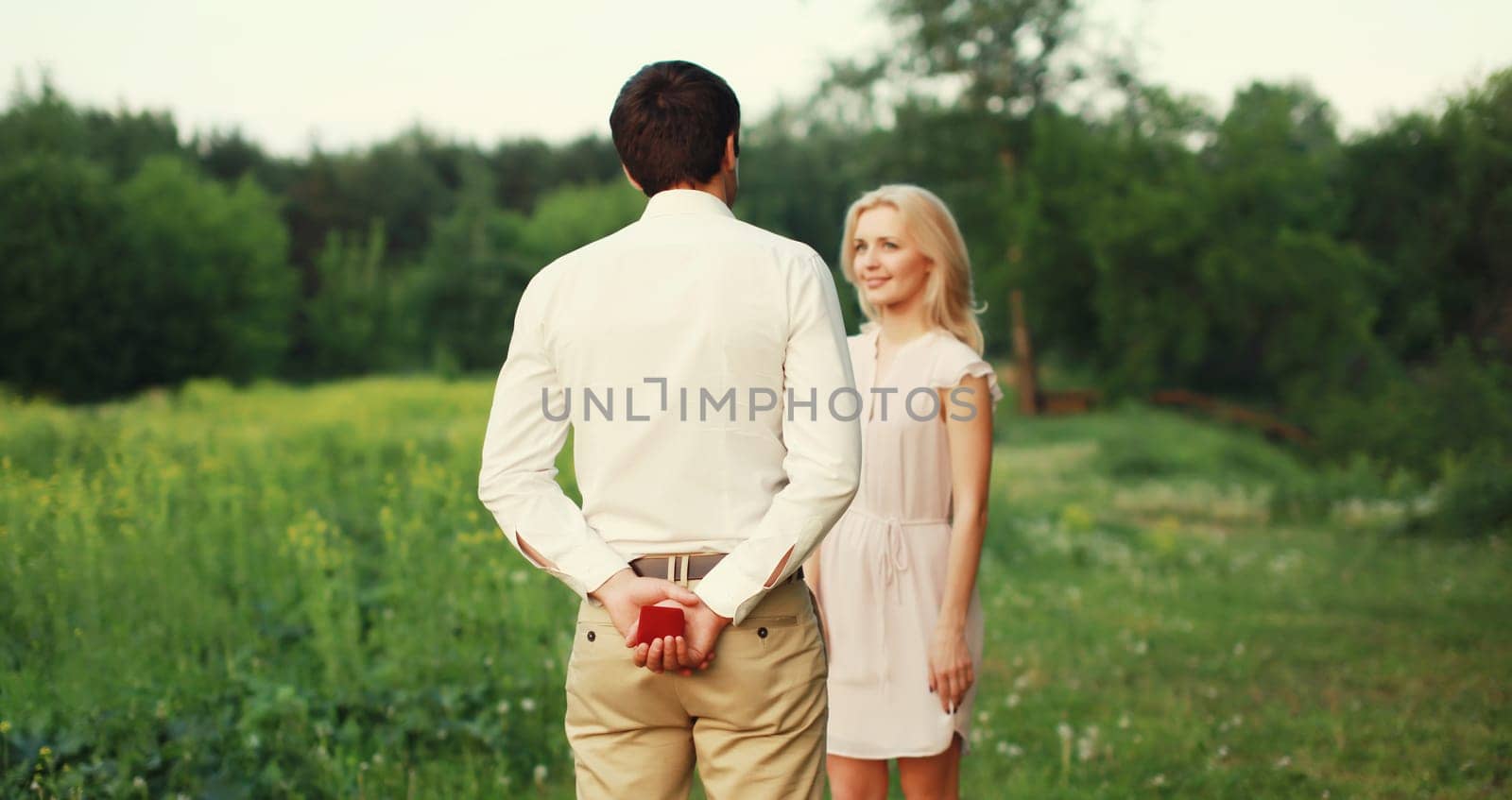 Wedding concept, happy lovely young couple, man proposing a ring to his beloved woman outdoors in summer park