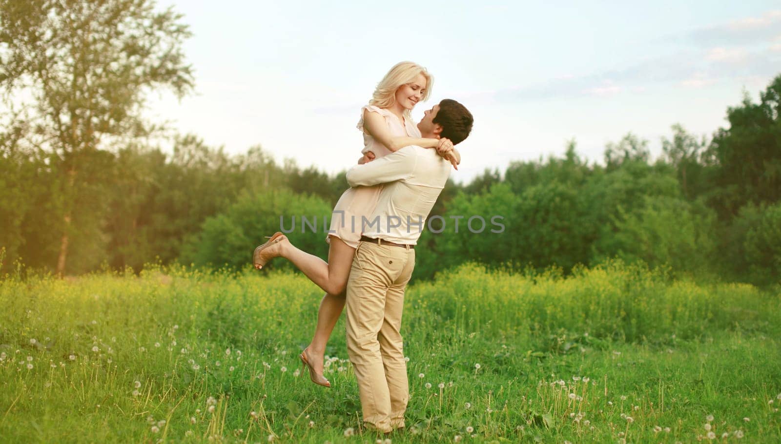 Portrait of beautiful happy smiling young couple in love together hugging in summer park by Rohappy