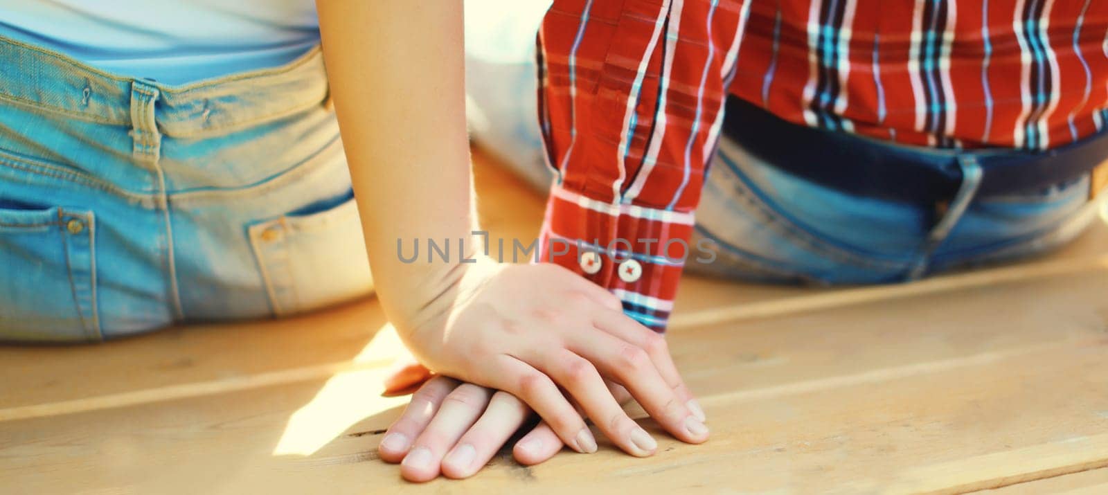 Close up of young couple holding hands, man and woman in love together in summer park