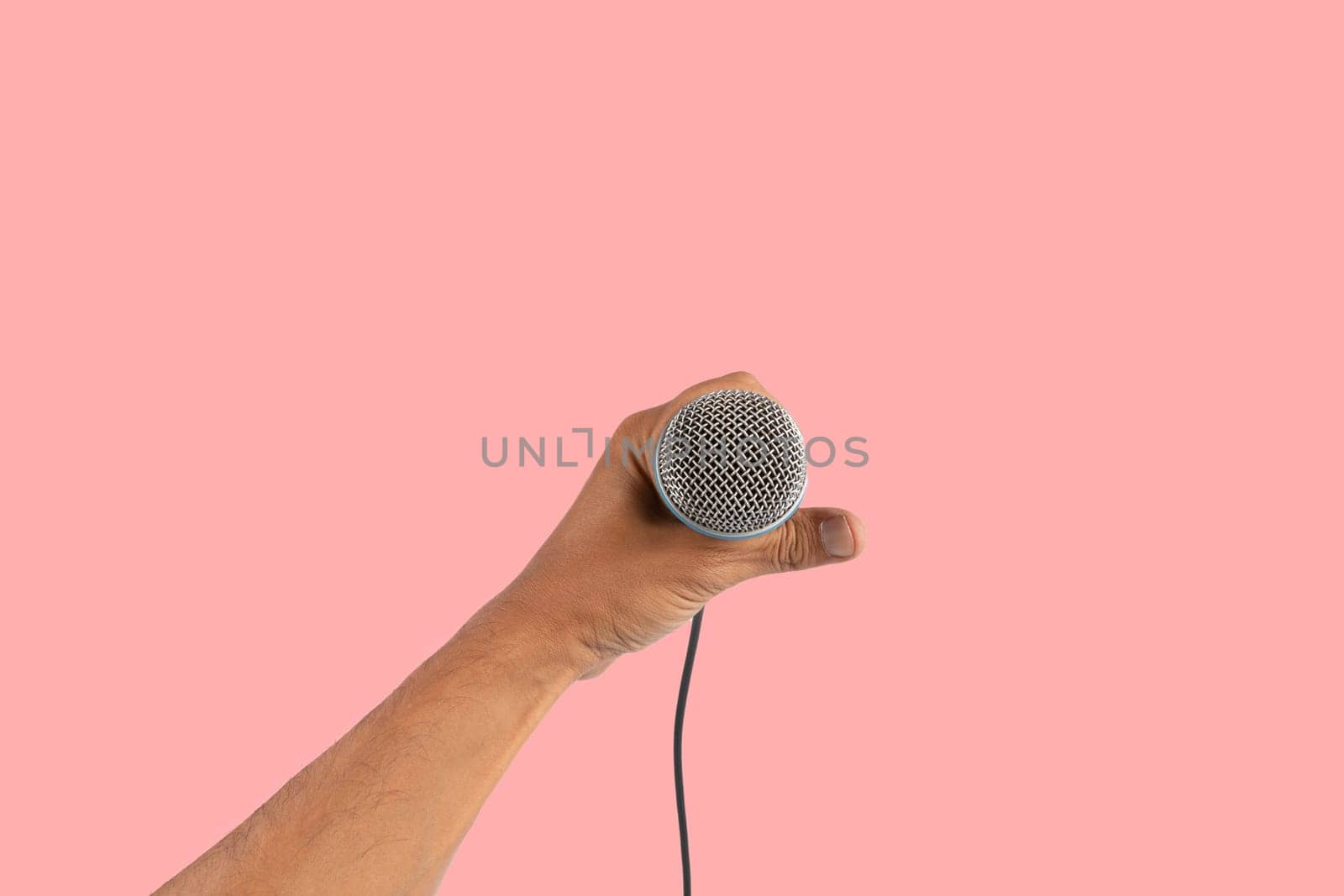 Black male singer hand holding a microphone isolated on pink background. High quality photo