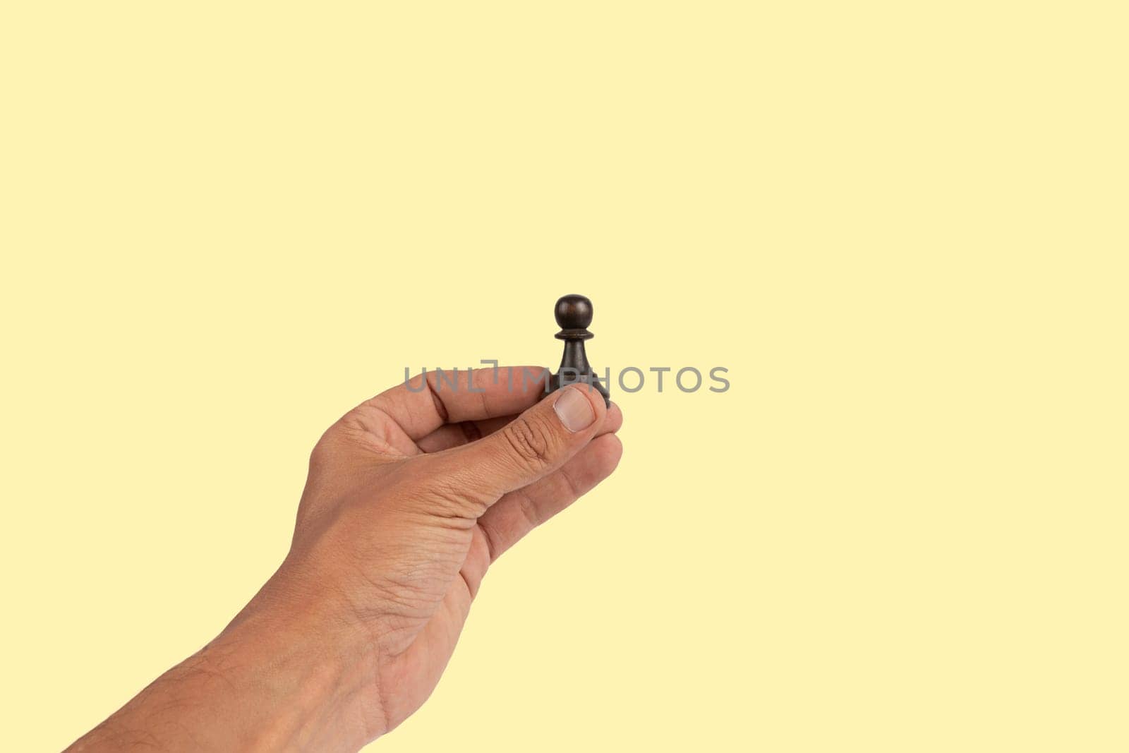 Isolated hand holding a chess figure on yellow background. High quality photo