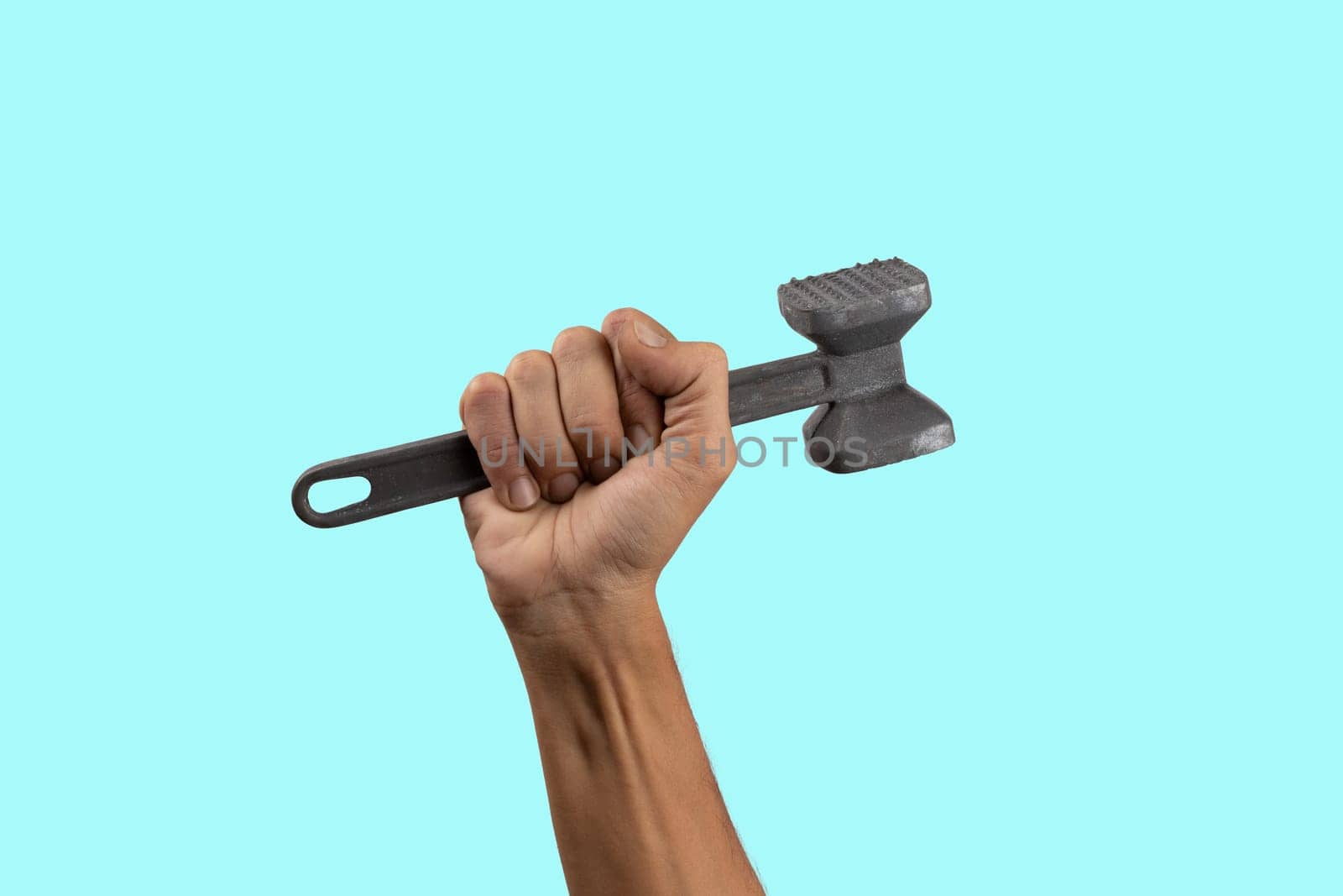 Black male hand holding a kitchen hammer isolated on cyan background. High quality photo