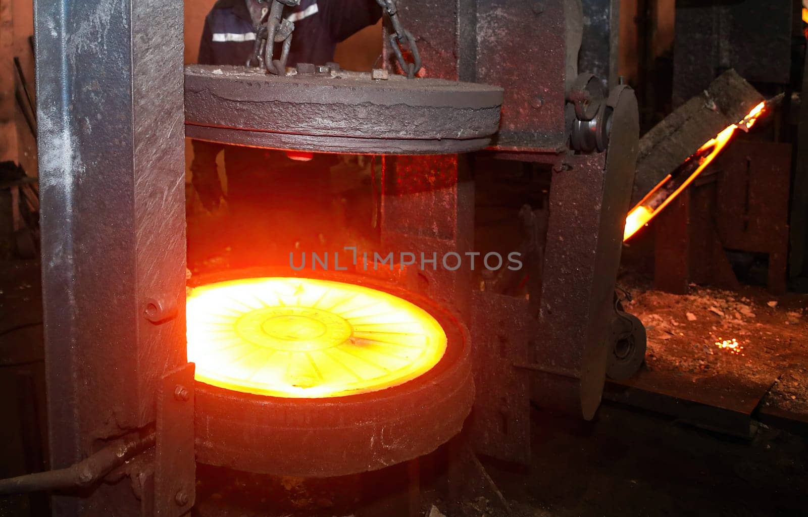 Industrial metalworking or manufacturing concept. Glowing hot round metal disc forging press isolated on black background. Industrial concept of power, energy, and strength.
