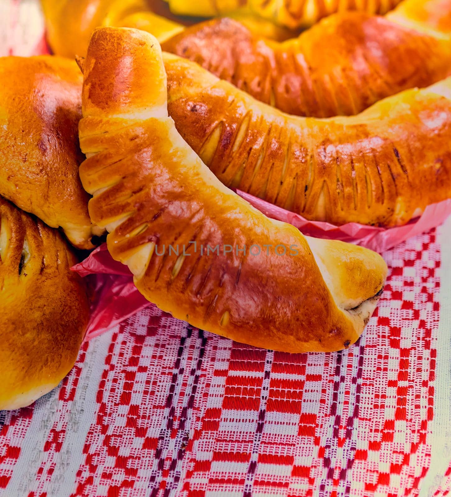 A close-up of freshly baked homemade puff pastry horns filled with rich chocolate cream on a red checkered tablecloth. Golden brown and flaky pastry, perfect for a sweet breakfast or snack.