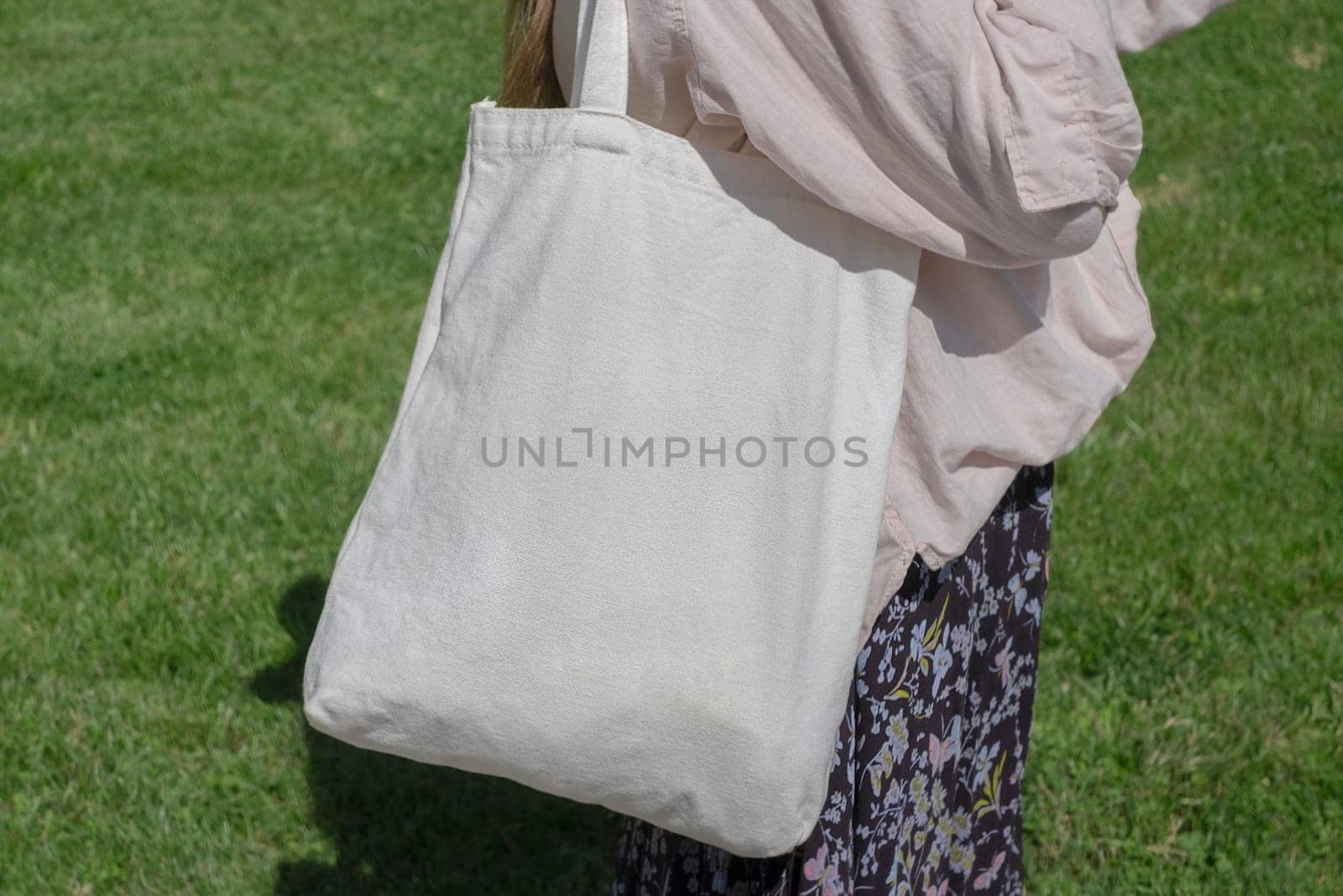 Girl with cotton white bag over her shoulder on green background. Mock up