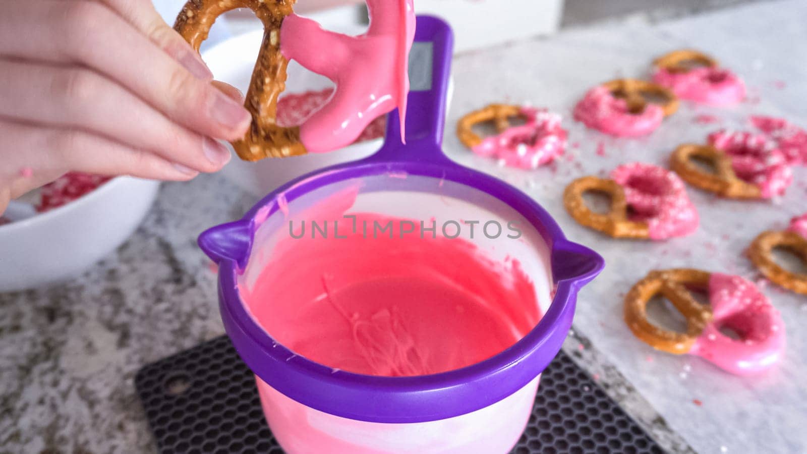 Freshly dipped and still glistening, these crunchy pretzels are lovingly adorned with pink chocolate and a scattering of colorful sprinkles, promising a feast for the senses.